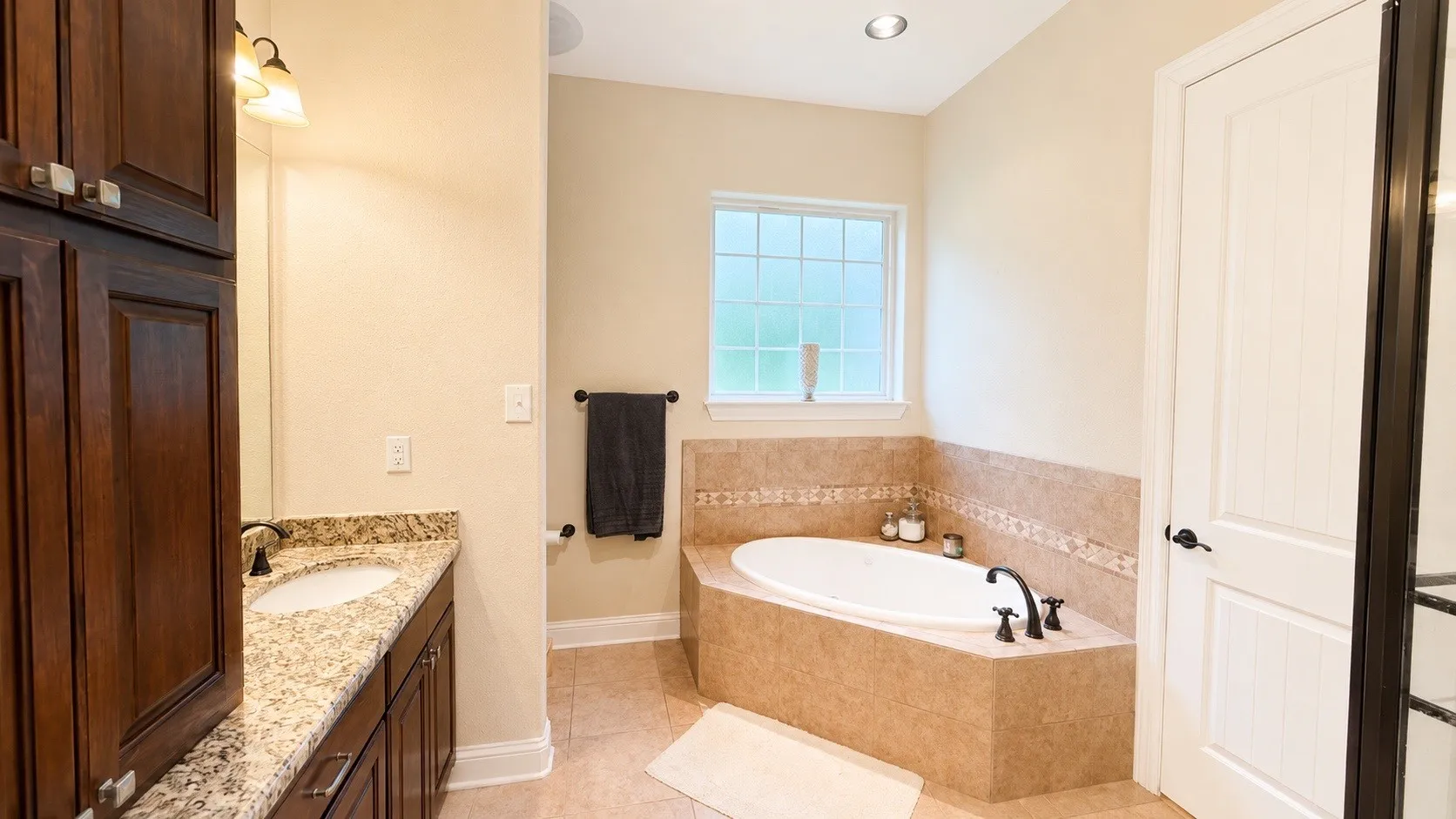 Built-in corner bathtub with tiled surround and decorative tile accent
