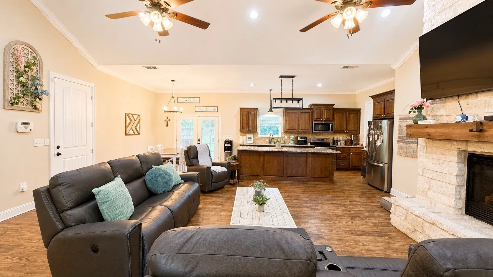 Open-concept living space featuring wood-finish flooring, a stone fireplace, and recessed lighting