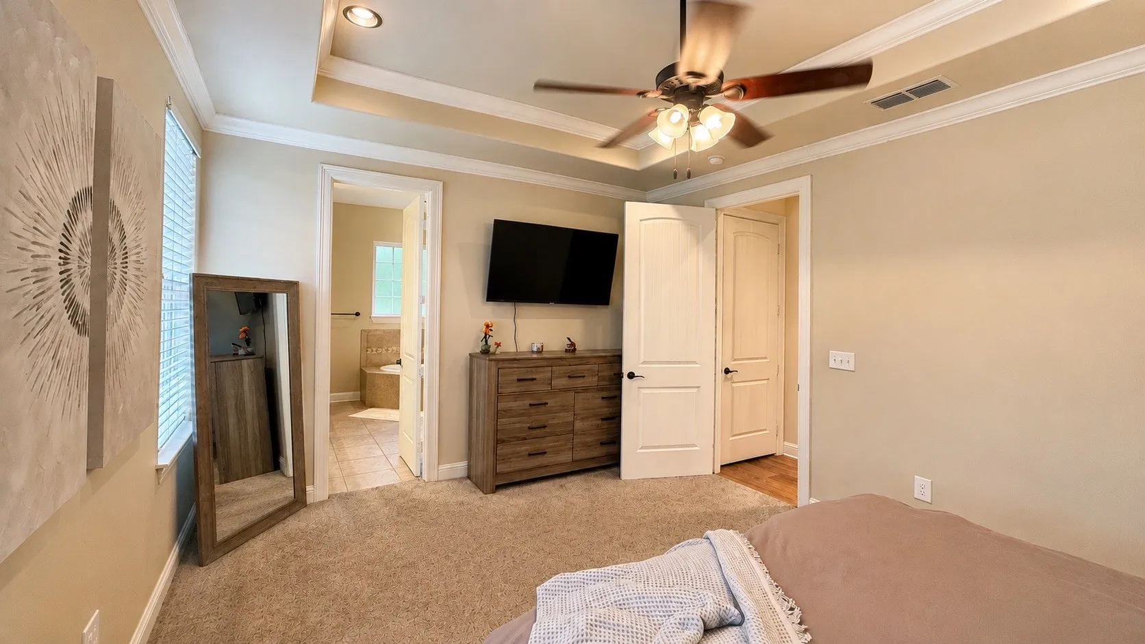Spacious room featuring tray ceiling with recessed lighting and a ceiling fan
