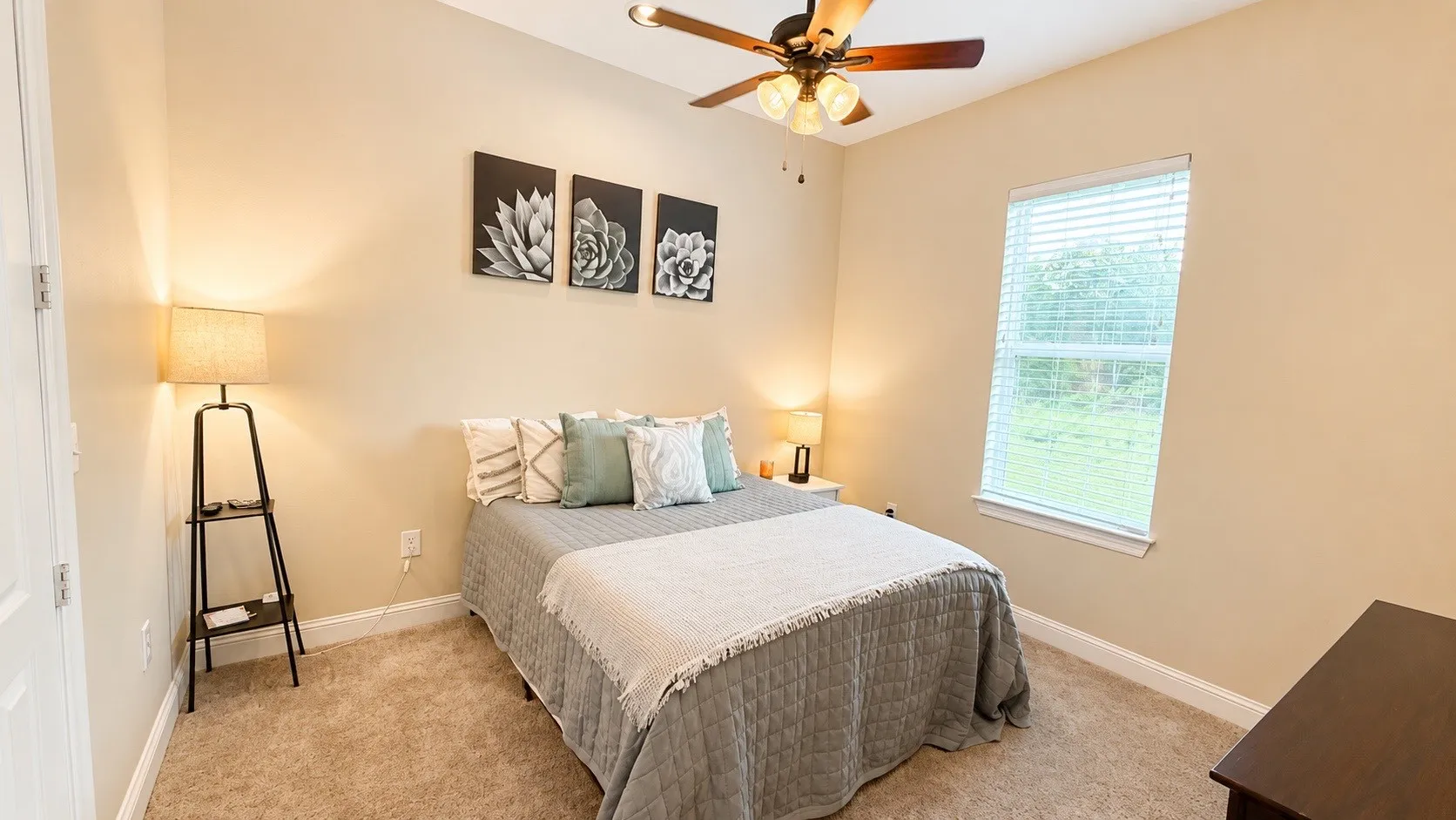 Carpeted room featuring a ceiling fan with light fixture, a window with blinds, and neutral painted walls
