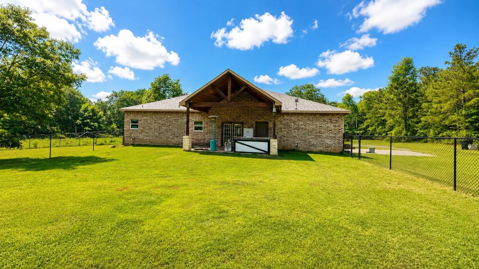 Expansive green lawn bordering a brick exterior with a covered patio