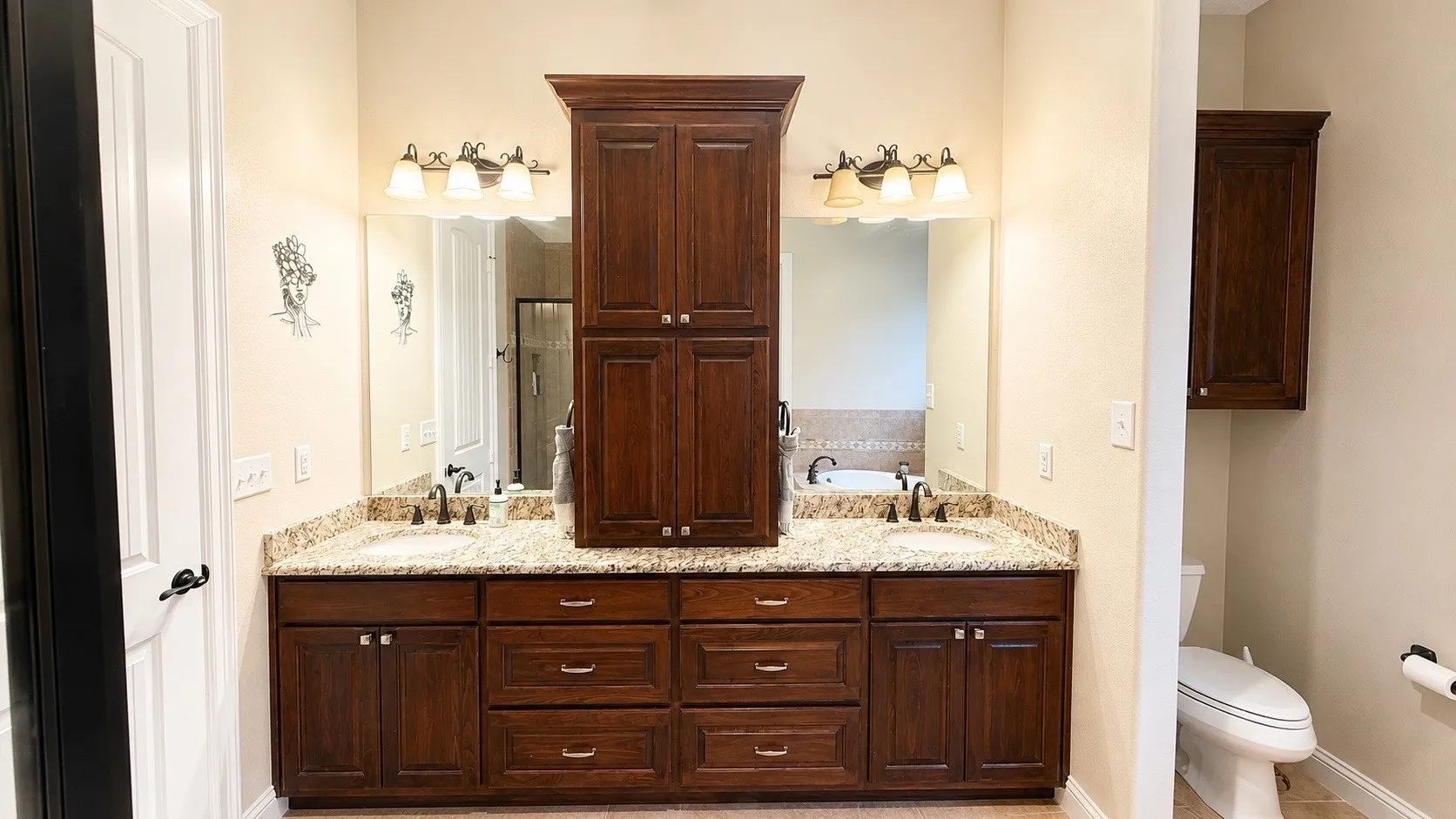 Double vanity with granite countertops, dual undermount sinks, and dark wood cabinetry