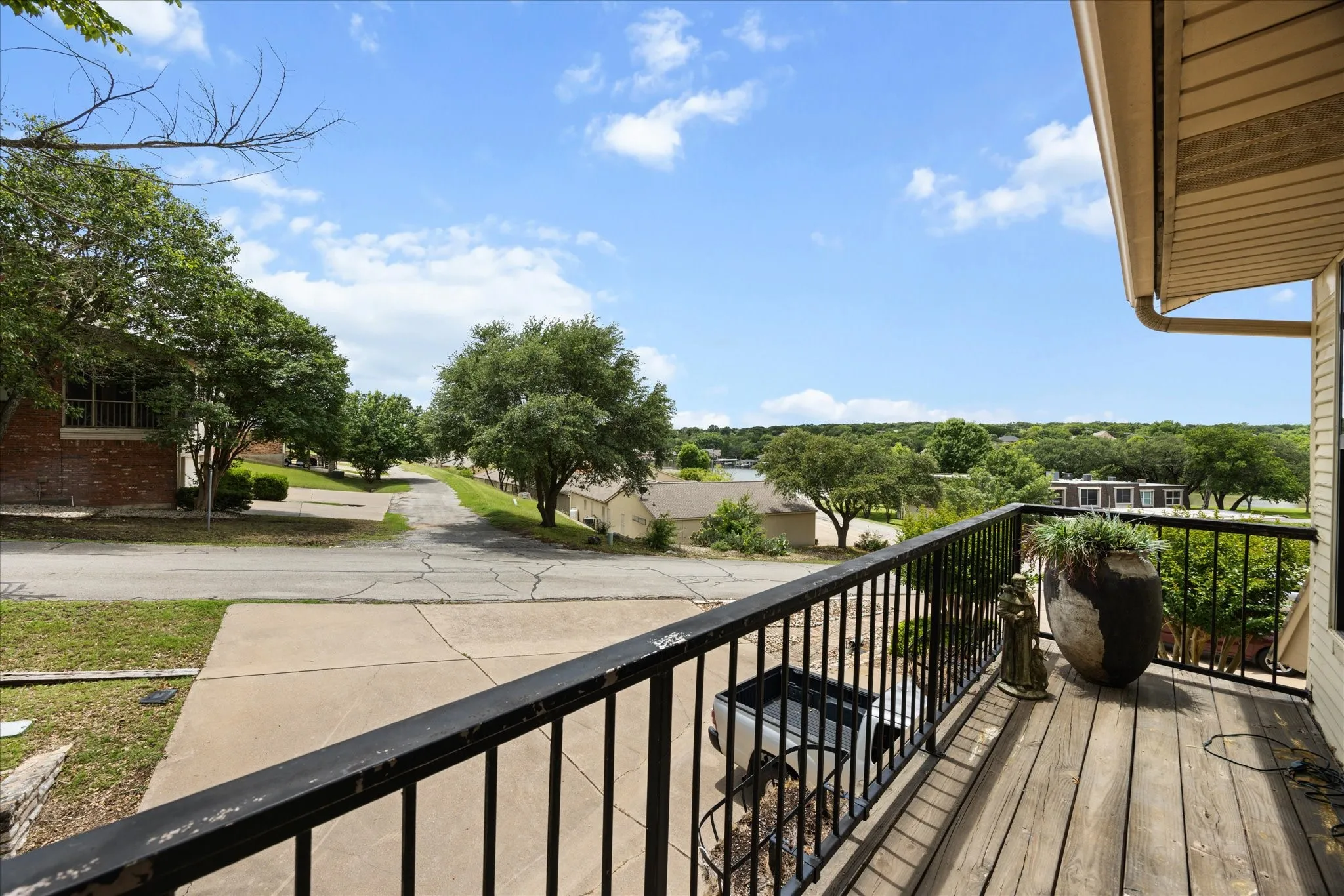 Exterior balcony featuring wood-finish decking and black wrought iron railing