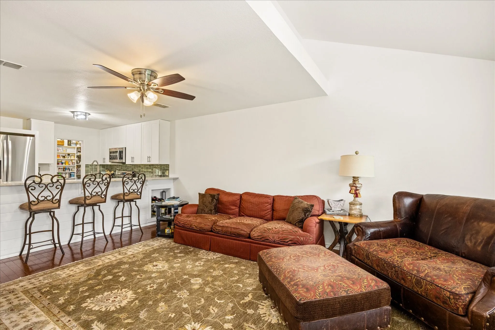 Open-concept living area featuring wood-finish flooring, a vaulted ceiling, and a ceiling fan