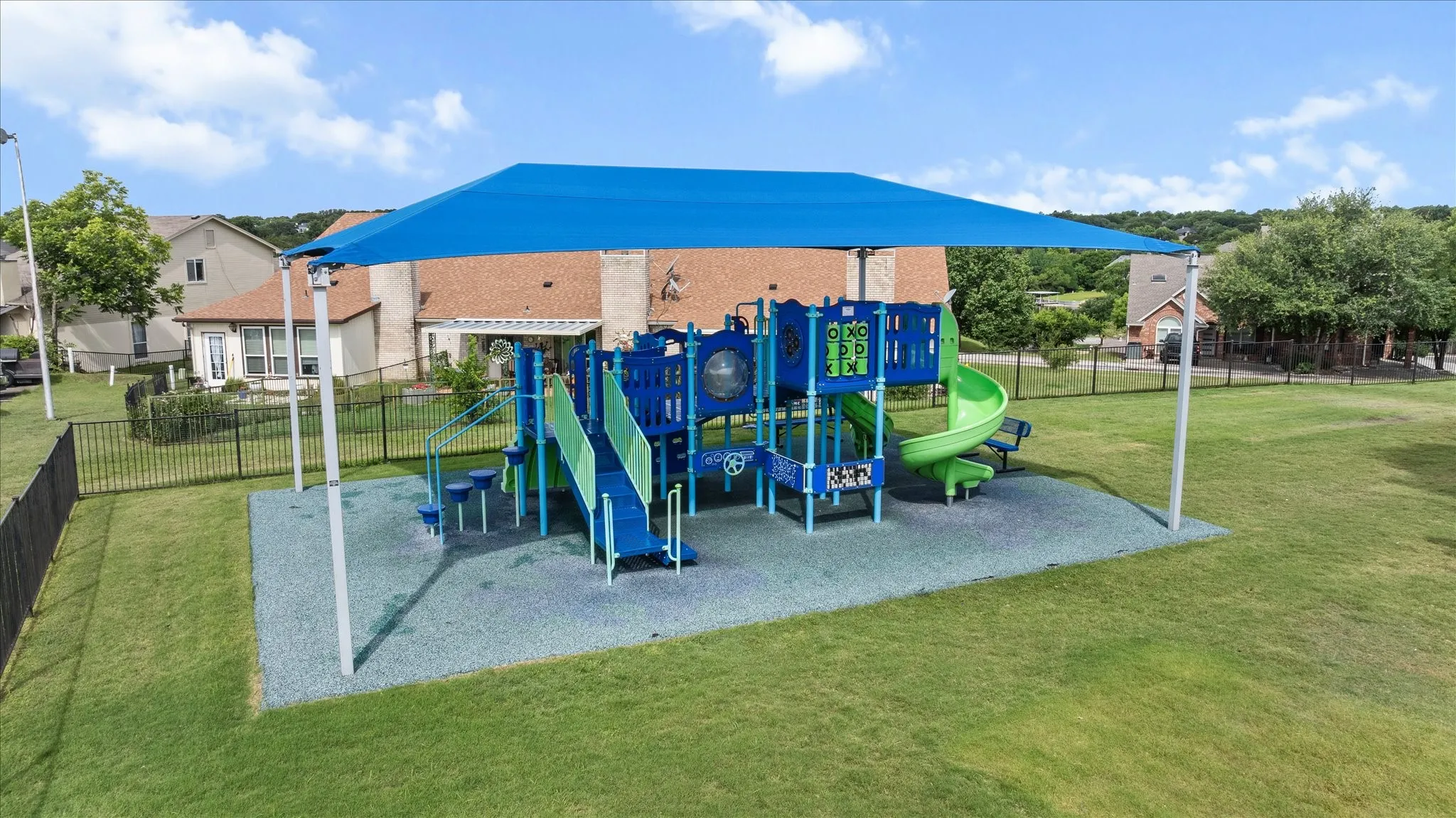 Outdoor play structure featuring multiple slides, climbing elements, and a vibrant blue shade canopy