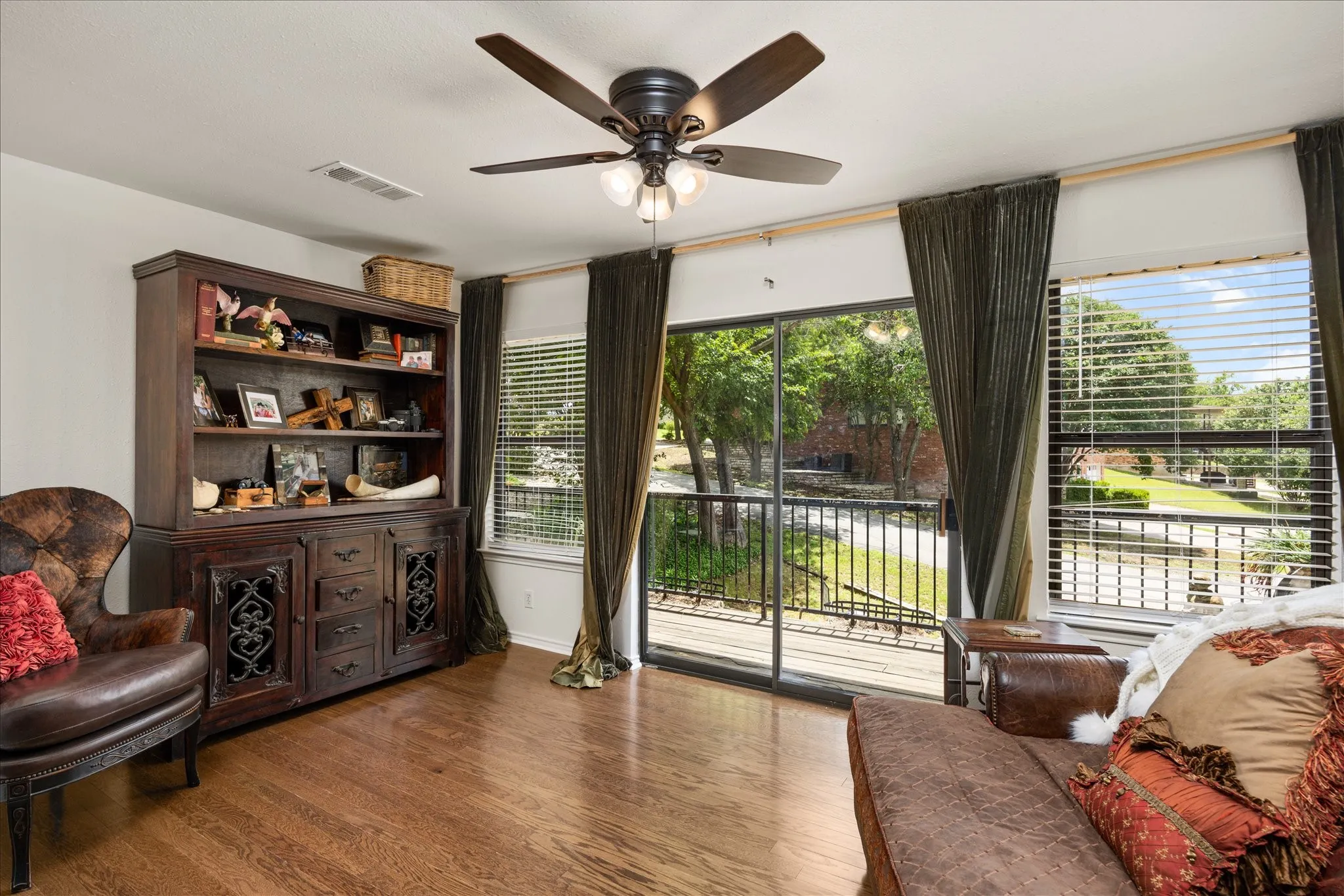 Room featuring wood-finish flooring, a ceiling fan with integrated lighting, and a built-in hutch with open shelving and cabinet storage