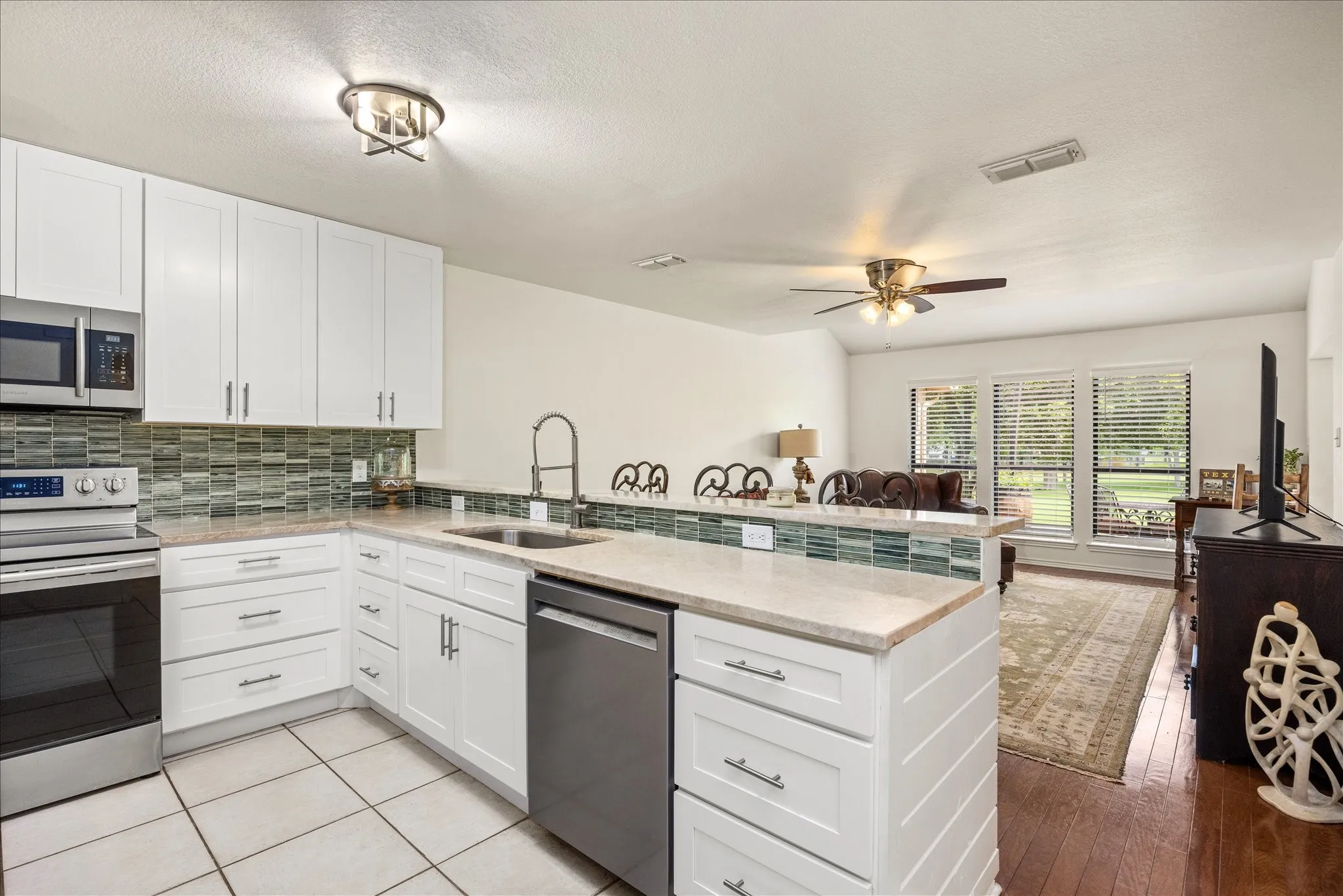 Contemporary kitchen featuring white cabinetry, light-toned countertops, stainless steel appliances, and tile flooring