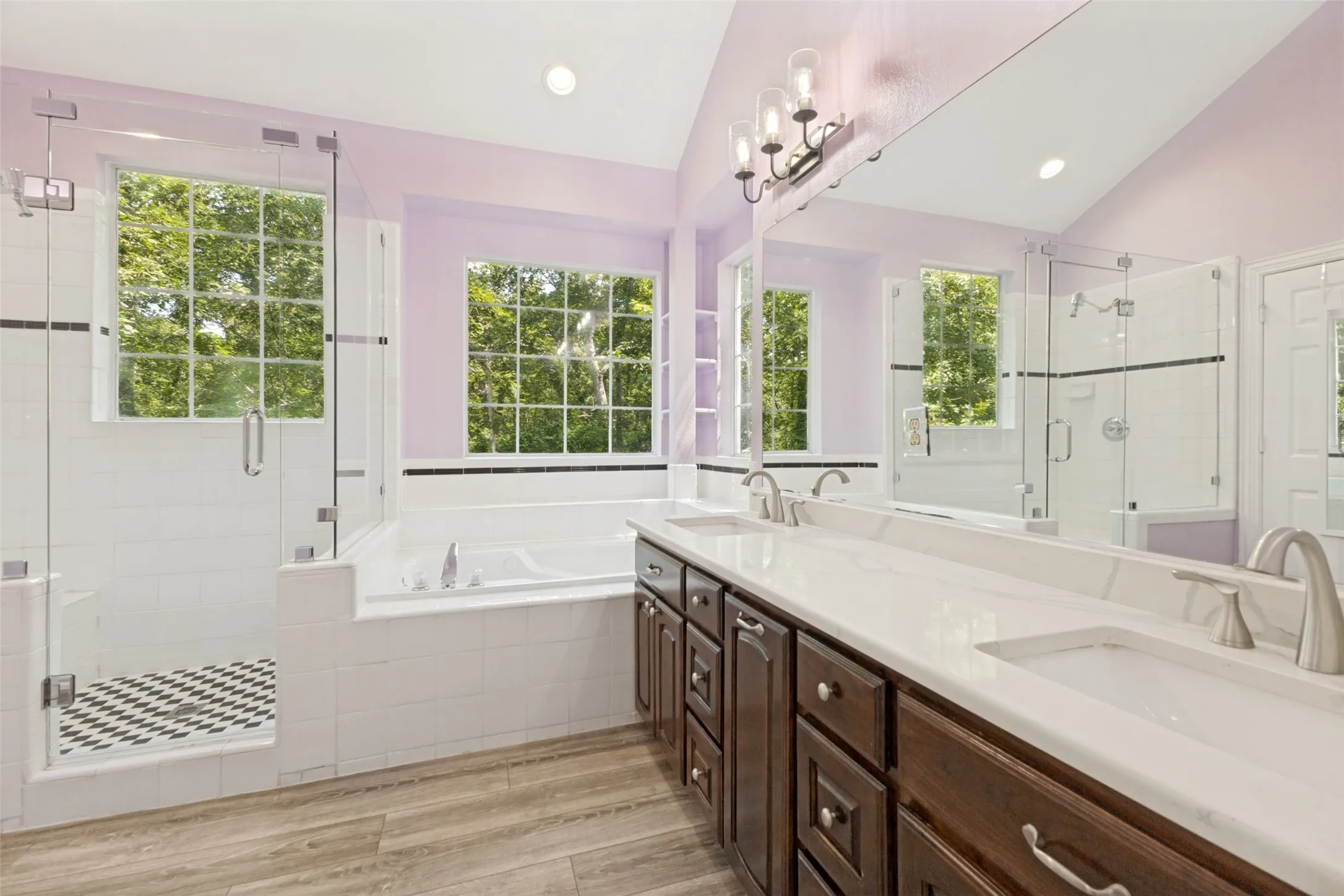 Dual vanity, warm wood cabinetry, frameless glass-enclosed shower and garden tub looking out into the parklike setting of this home!