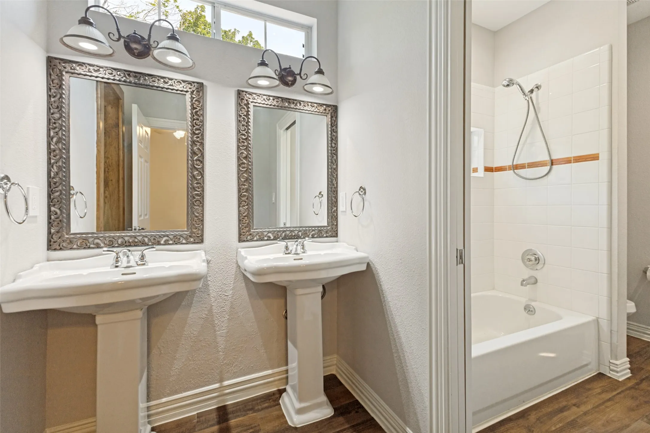 Upstairs Bathroom featuring dual pedestal sinks and separated room with bath shower combo.