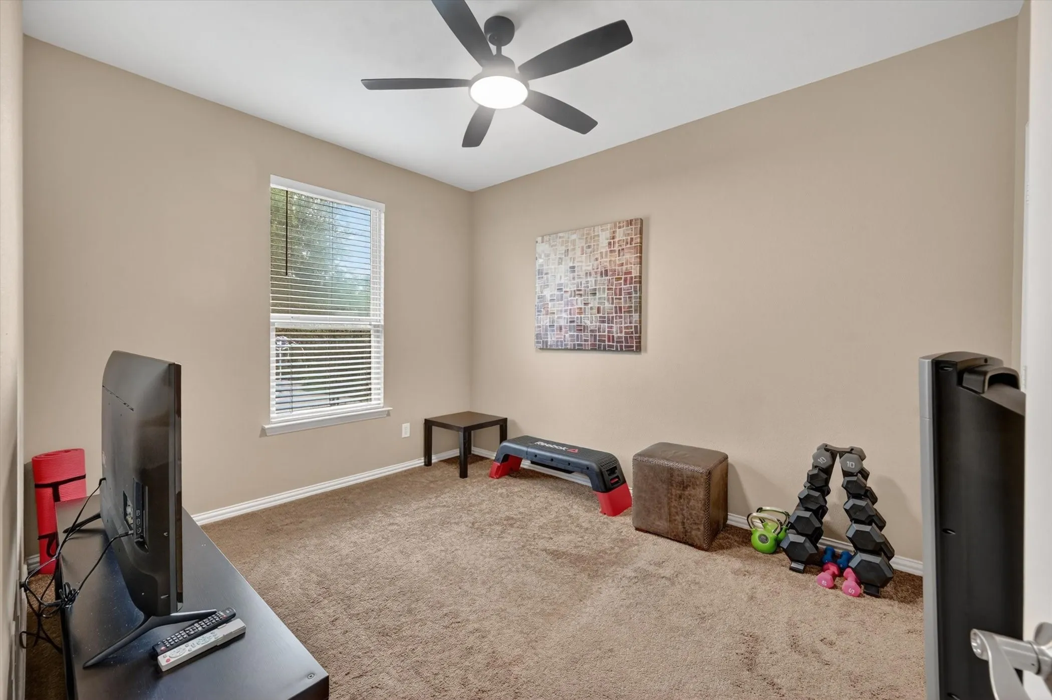 Neutral-toned room featuring a single window with blinds, a ceiling fan, and carpeted flooring