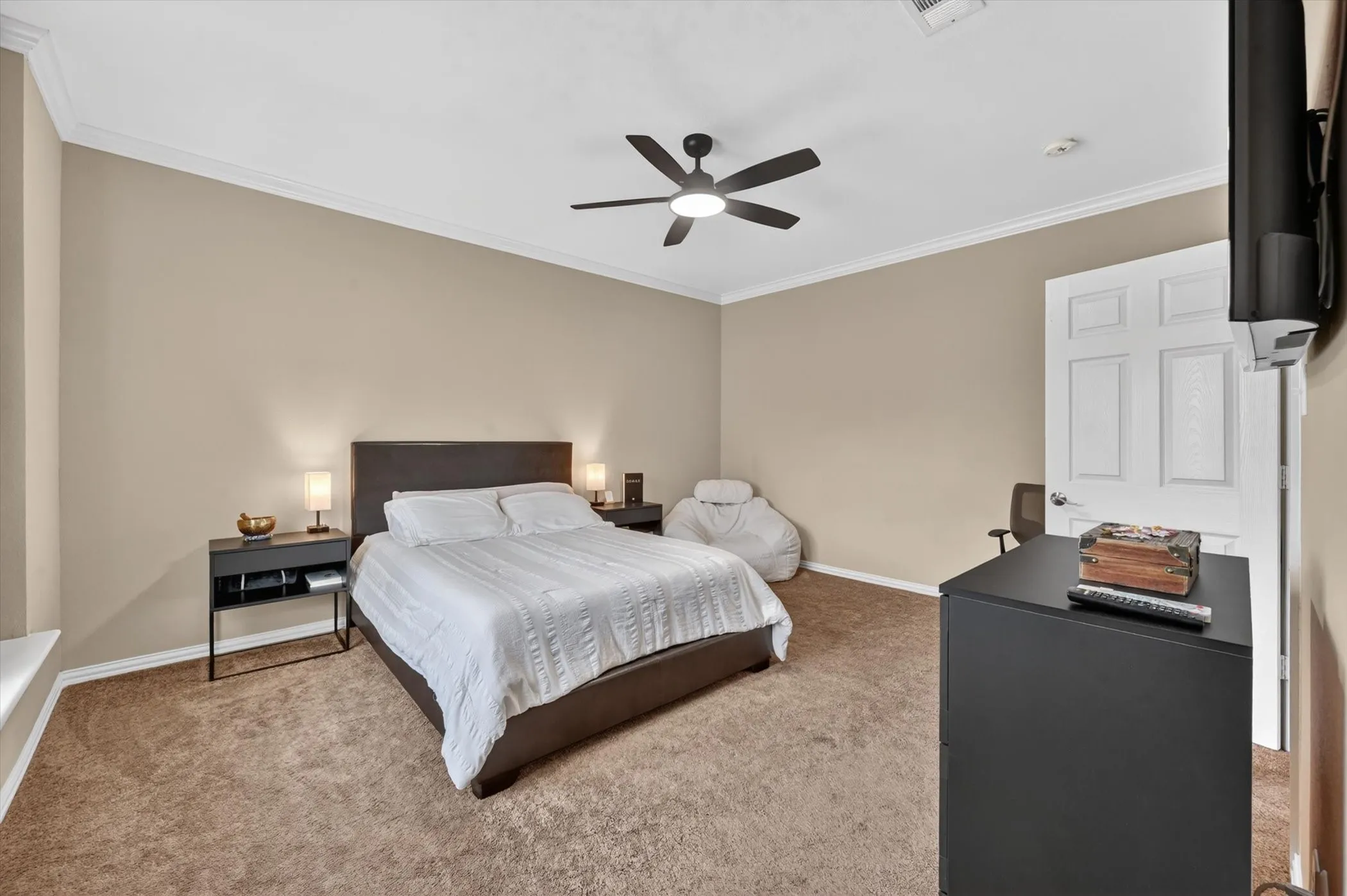 Carpeted interior space featuring a ceiling fan with integrated lighting, neutral wall tones, and white crown molding