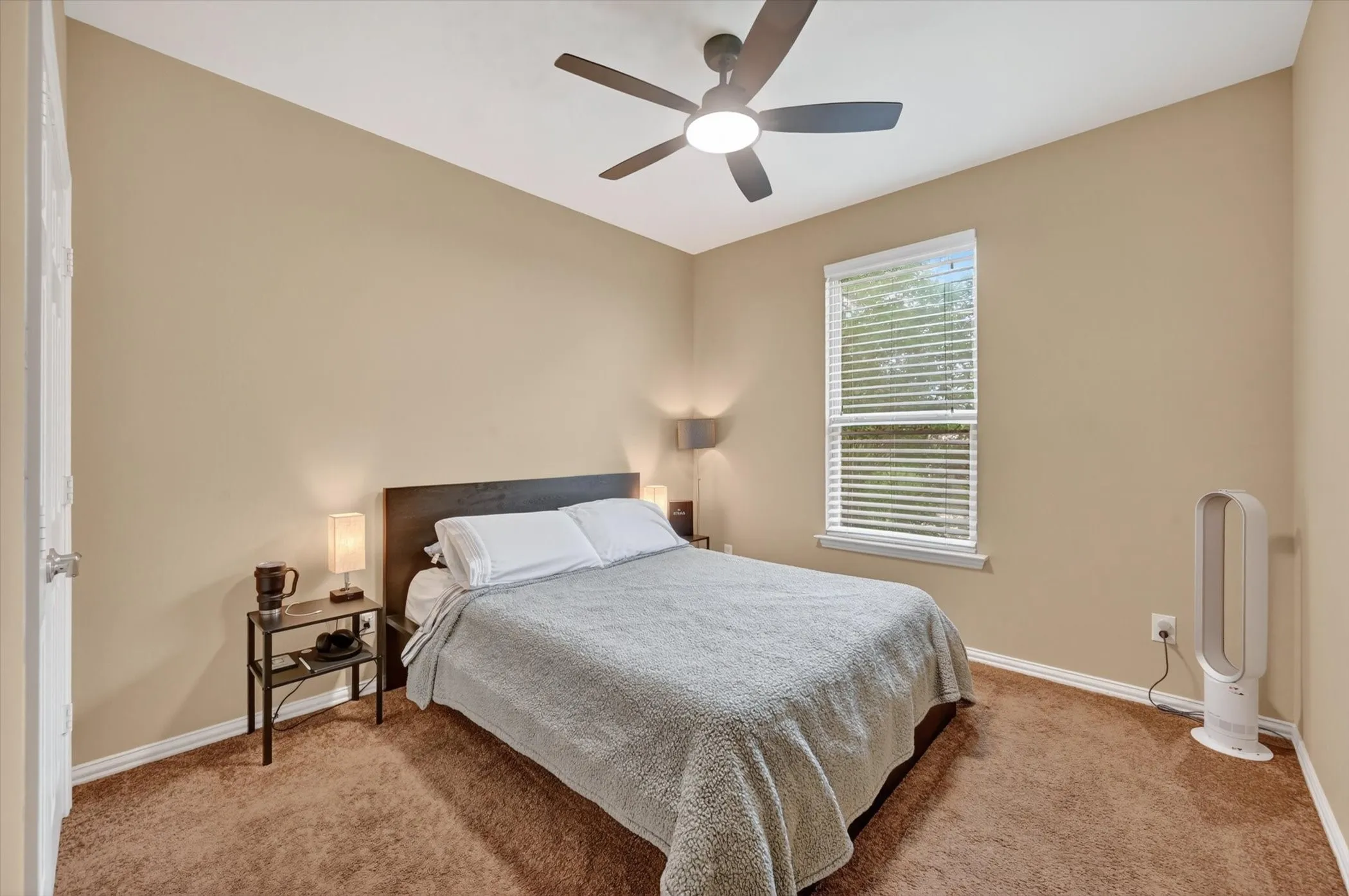 Bedroom featuring neutral-toned walls, brown carpet, and a window with blinds