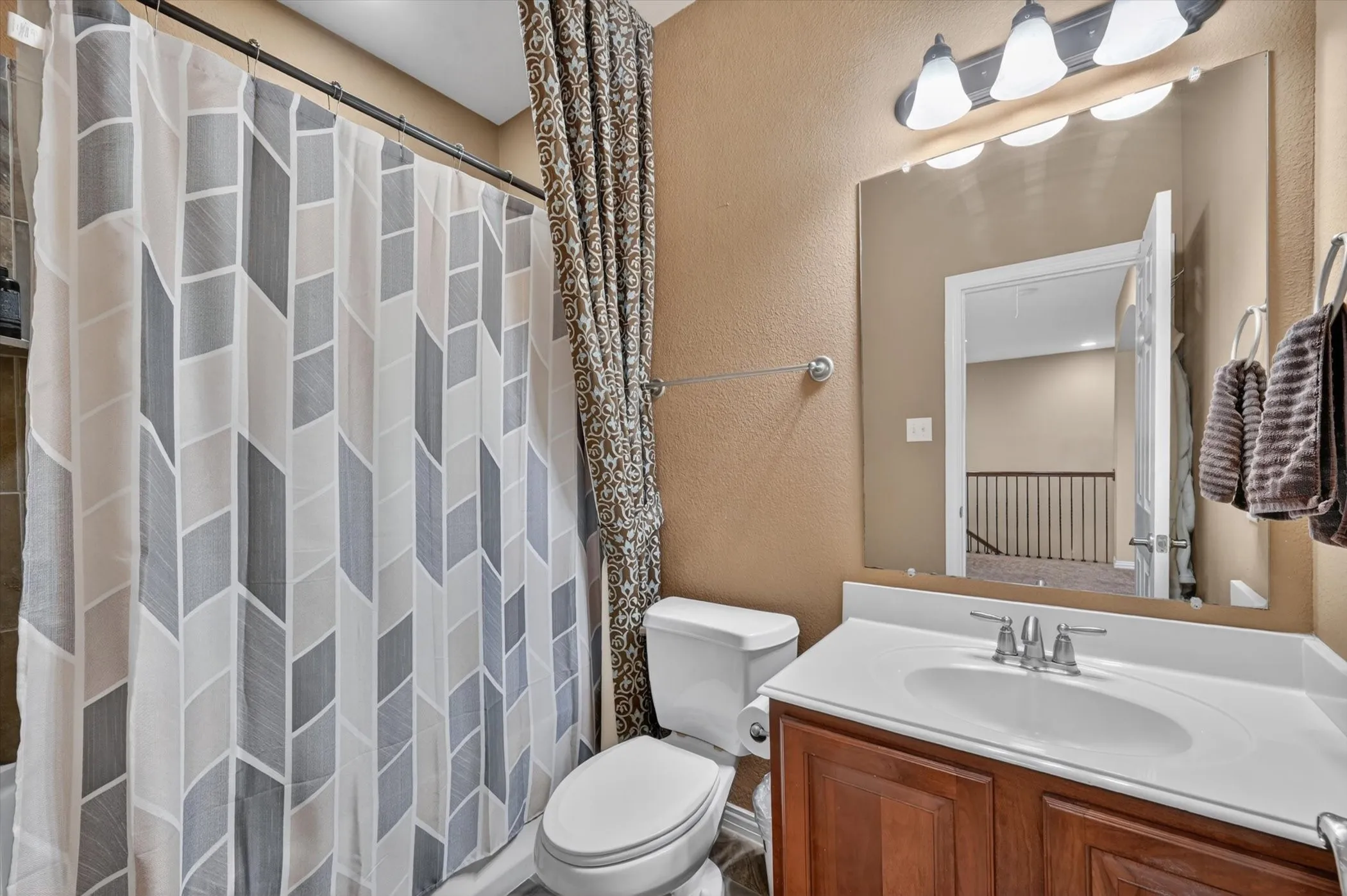 Bathroom featuring a wood-finish vanity with an integrated sink, polished chrome faucet, and a large wall-mounted mirror