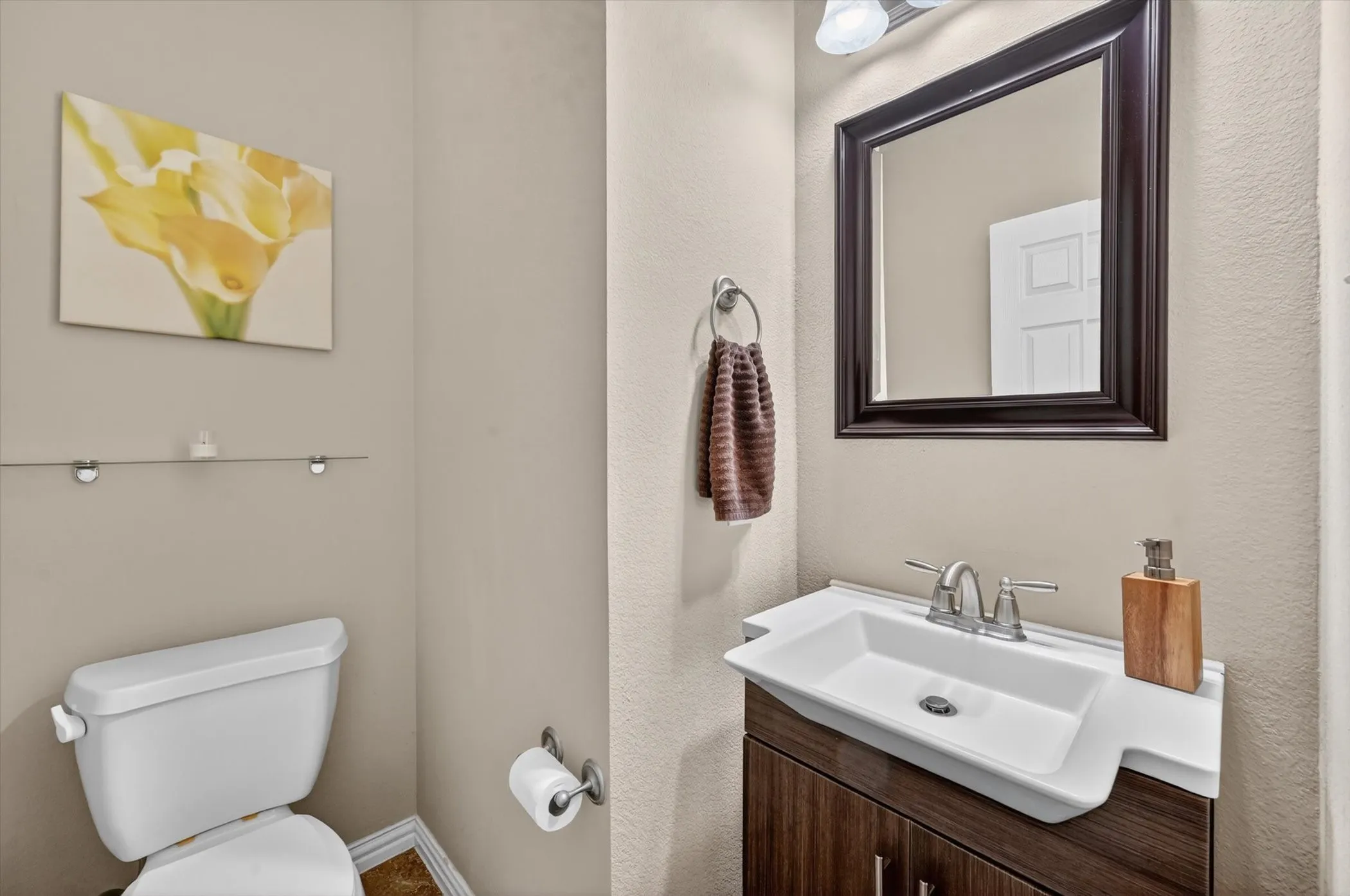 Bathroom vanity featuring a vessel sink, dark wood-finish cabinetry, and a framed mirror