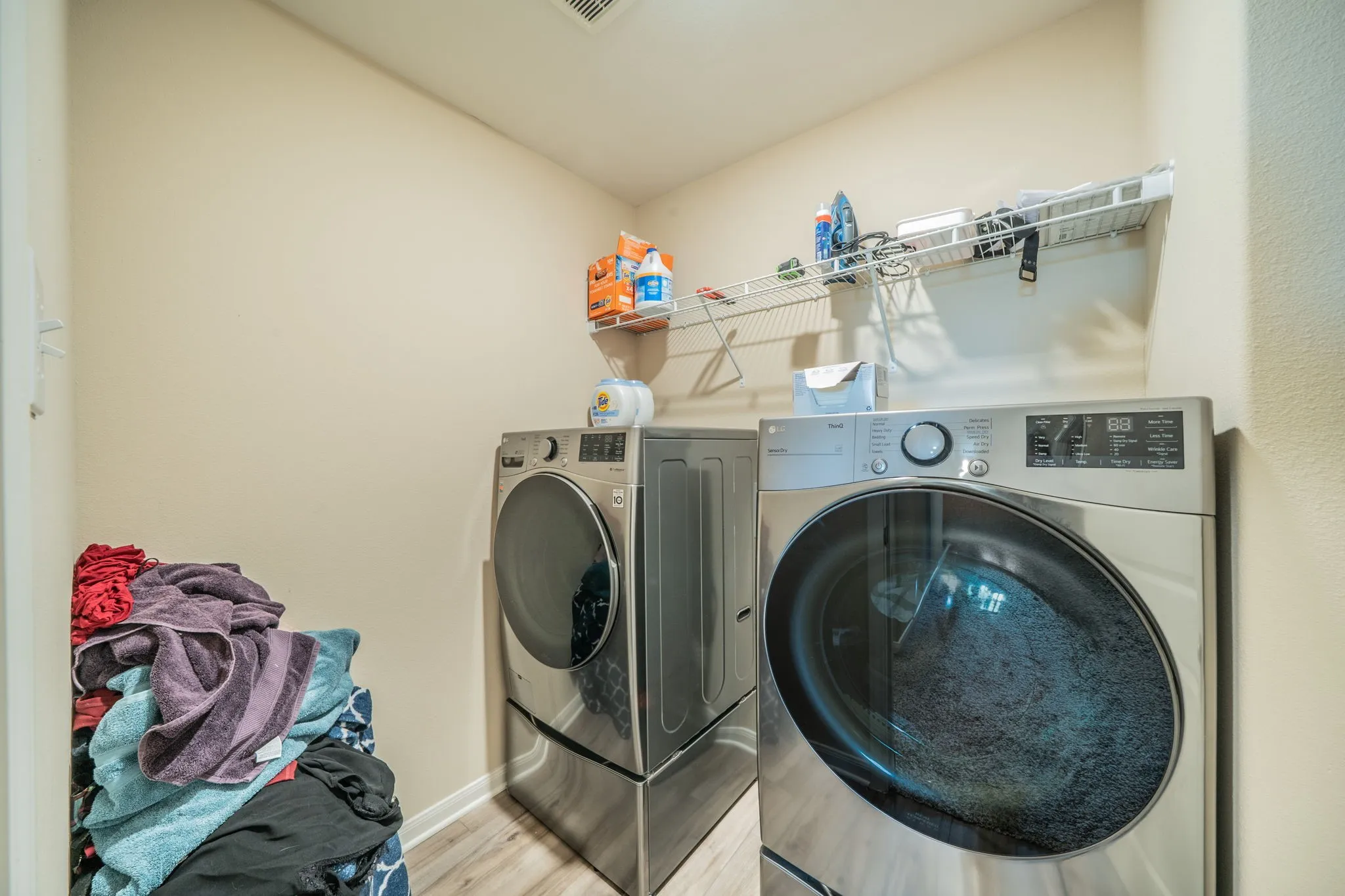 Dedicated laundry area featuring wire shelving and wood-finish flooring
