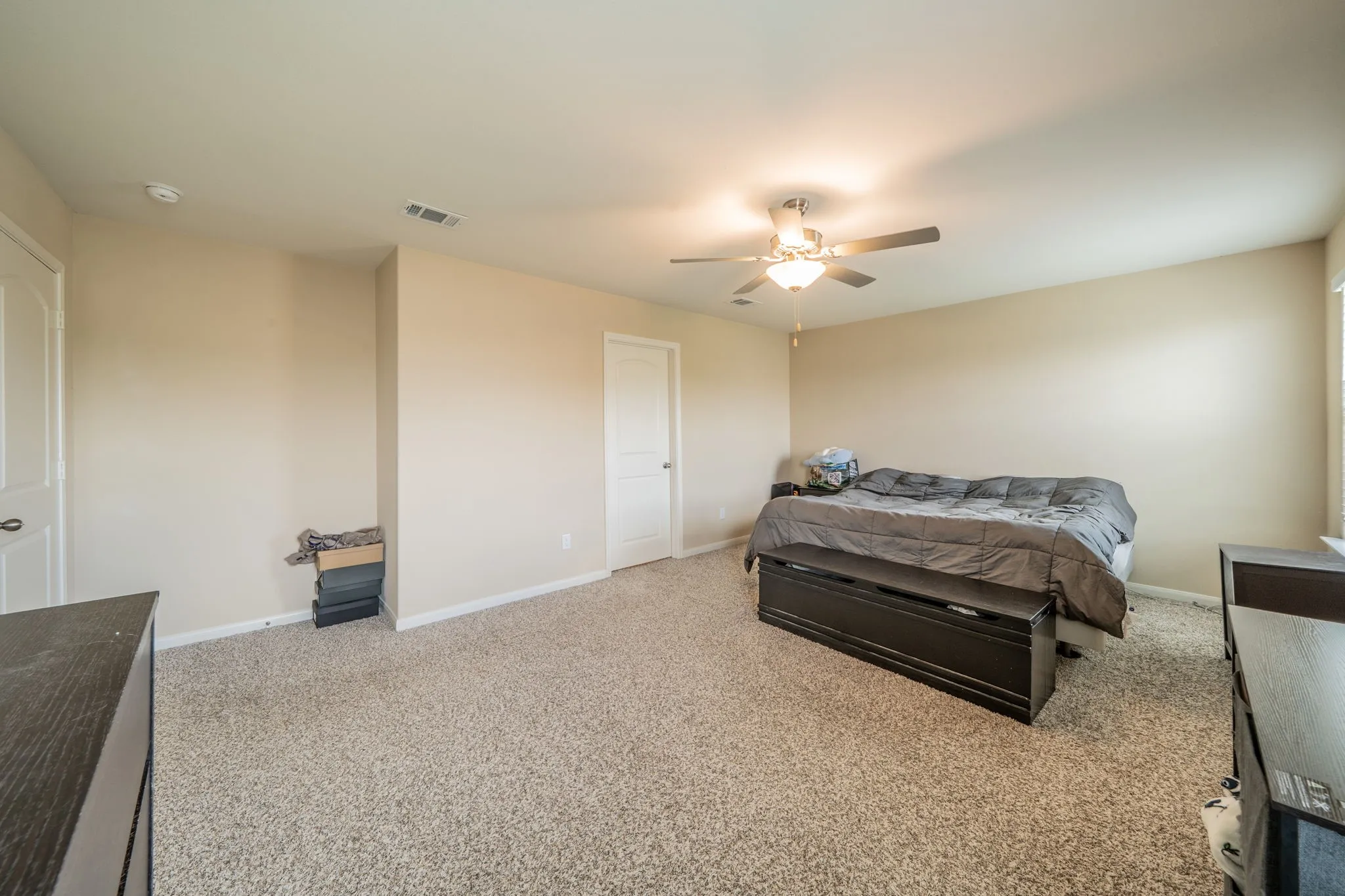 Spacious room featuring neutral carpet flooring, light beige walls, and white trim