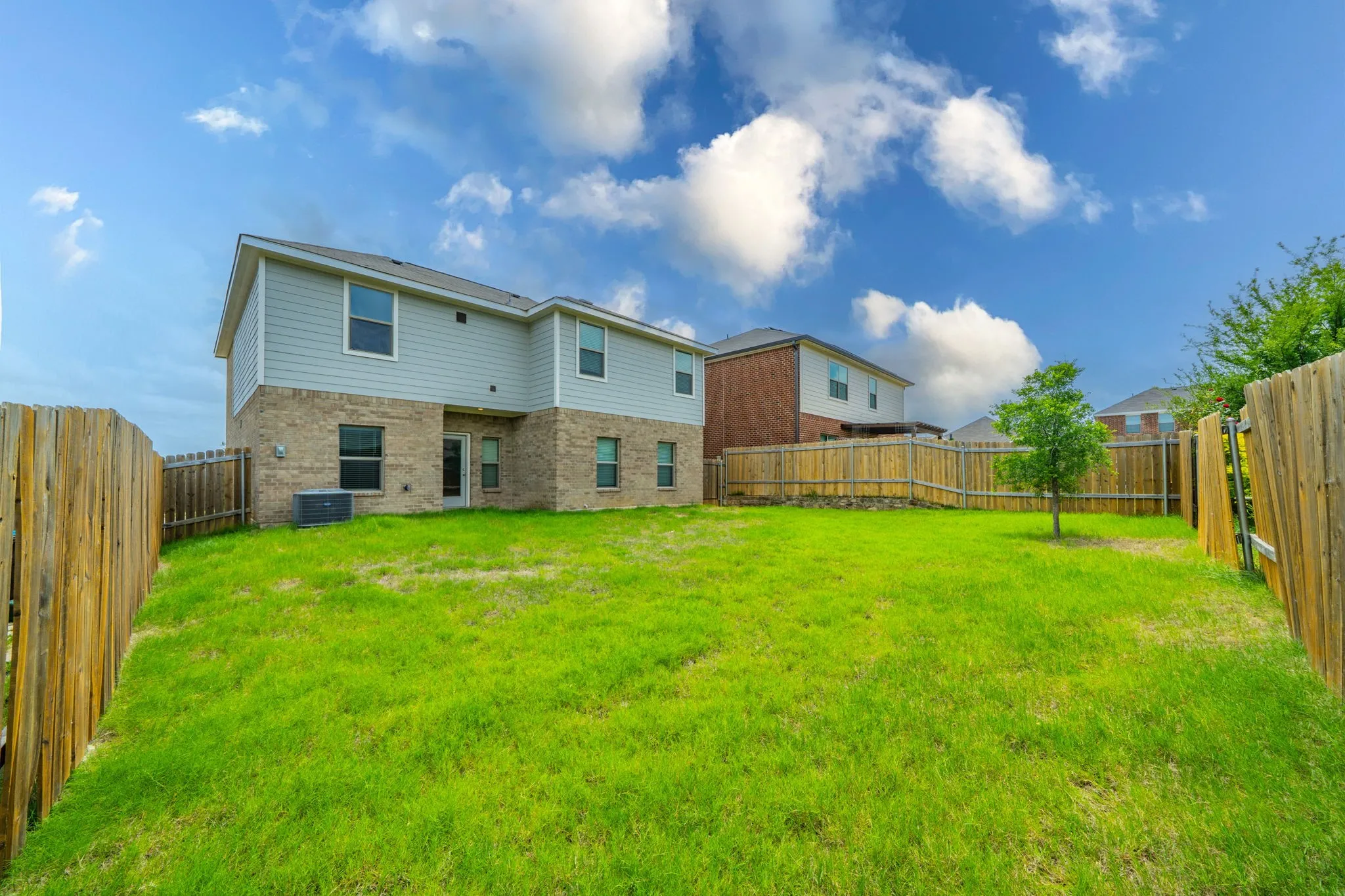 Expansive grassy backyard featuring a full privacy fence