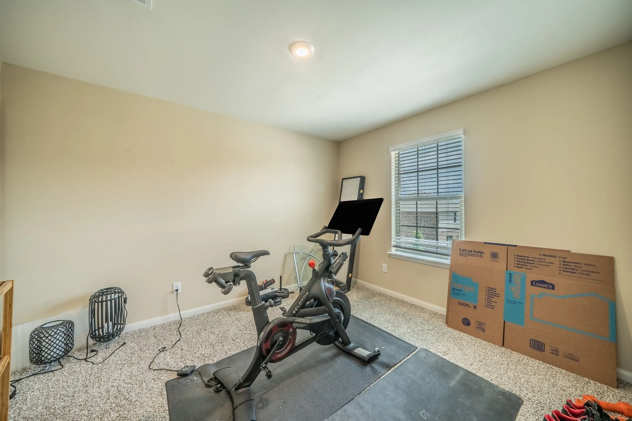 Carpeted interior room with neutral-toned walls, featuring a single window with blinds, and recessed lighting