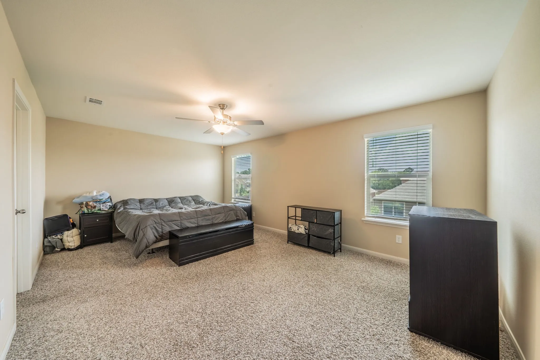 Carpeted room featuring a ceiling fan with integrated lighting, two windows with horizontal blinds, and a neutral wall color