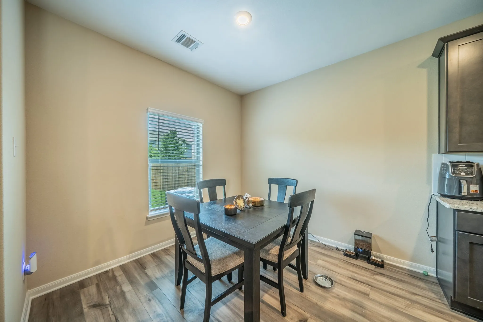 Dining space featuring wood-finish flooring, a single window with blinds, and light-toned walls