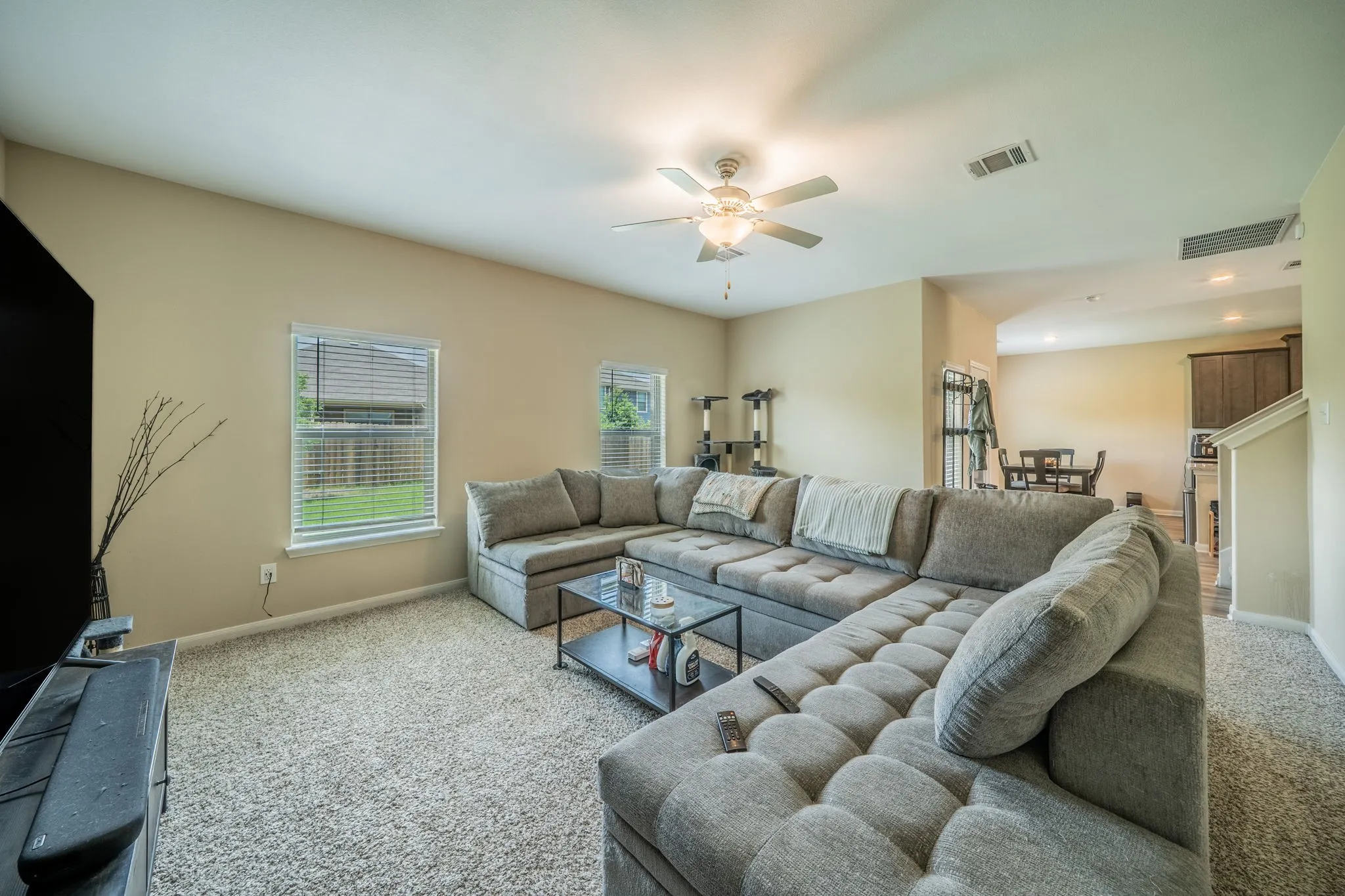 Spacious living area featuring neutral-toned walls, plush carpeting, and multiple windows