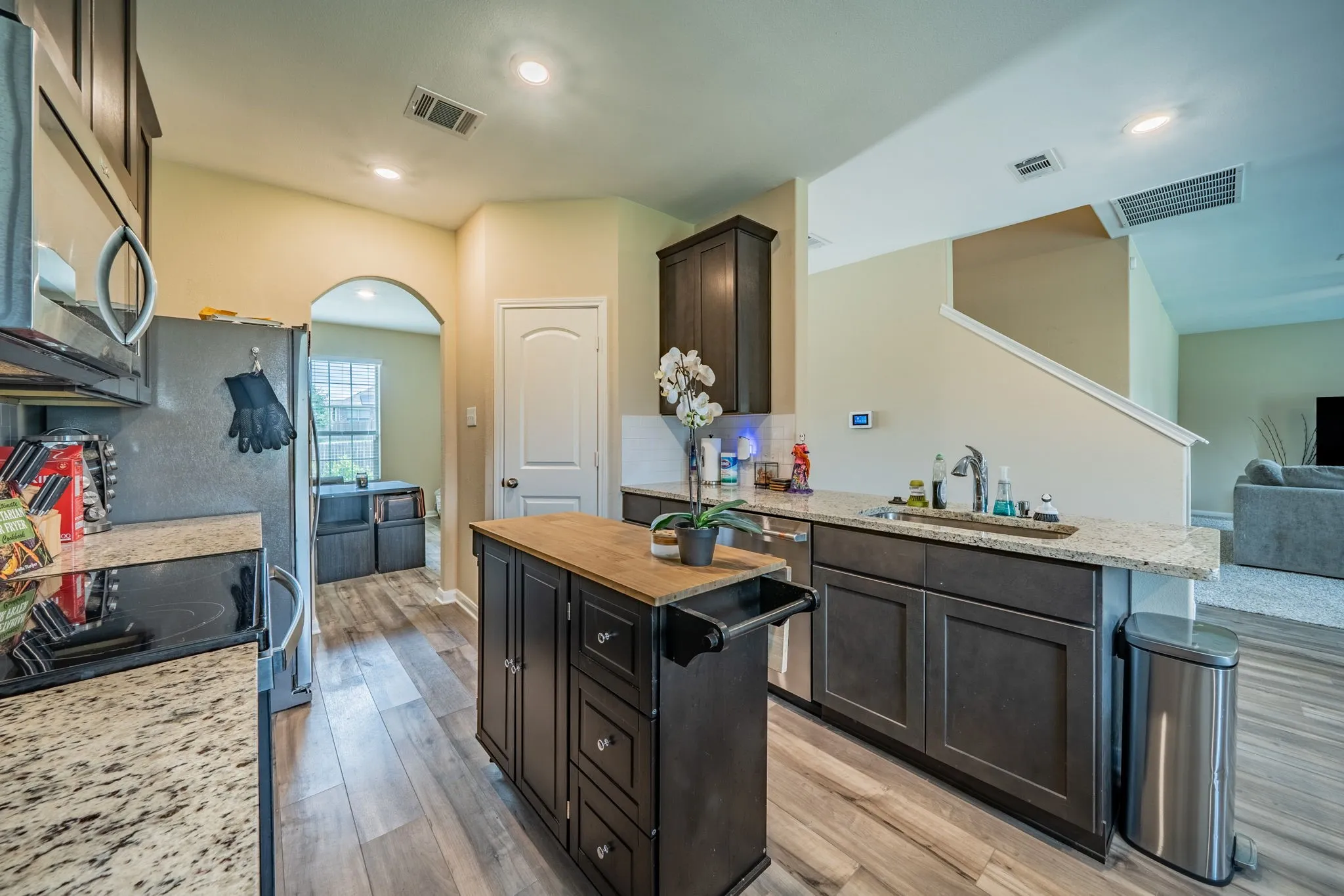 Kitchen featuring wood-finish flooring, dark cabinetry, light-toned countertops, and a central island with a wood-finish top