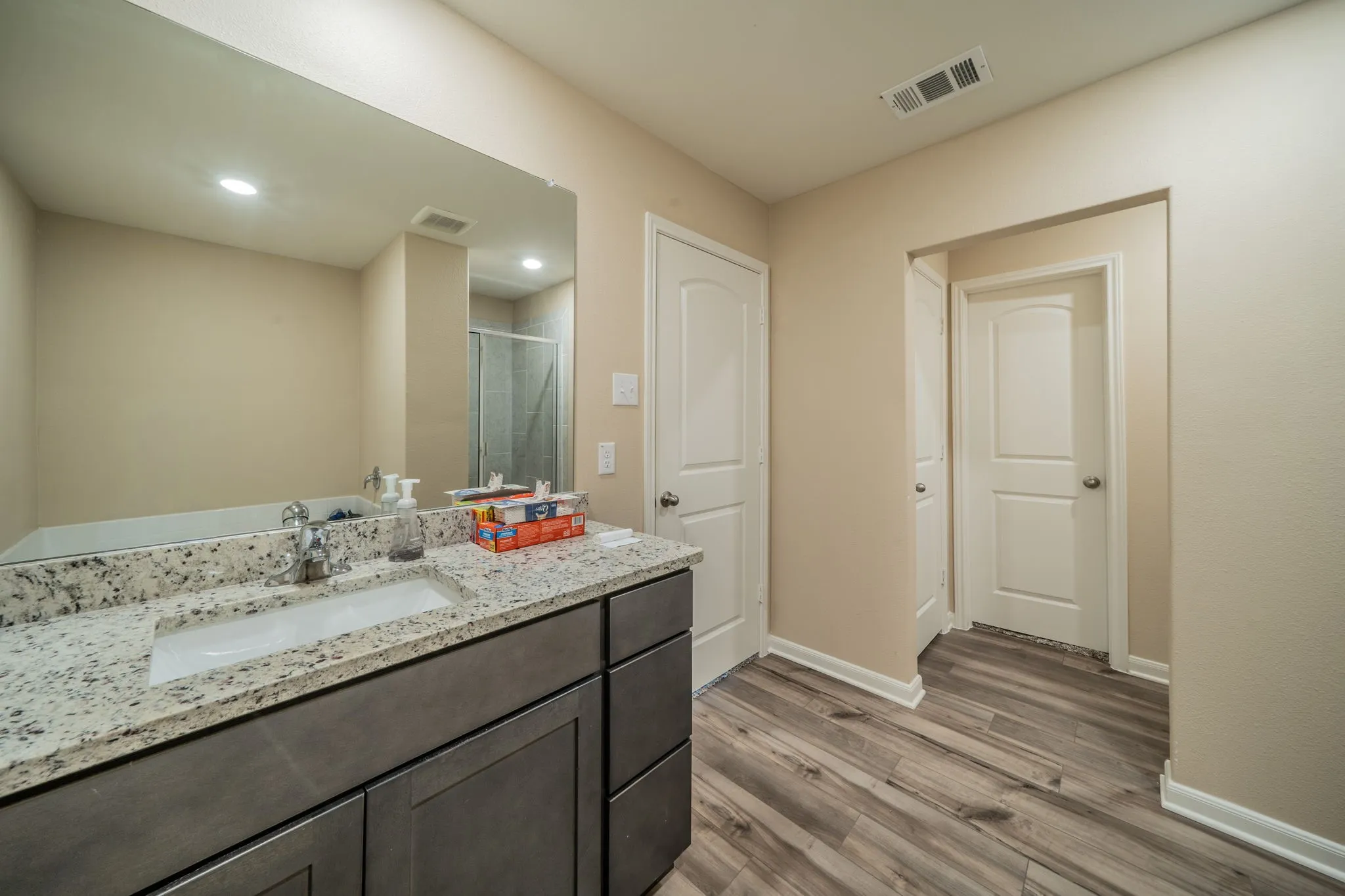Bathroom featuring a vanity with a light speckled countertop, an undermount sink, and dark wood-finish cabinetry