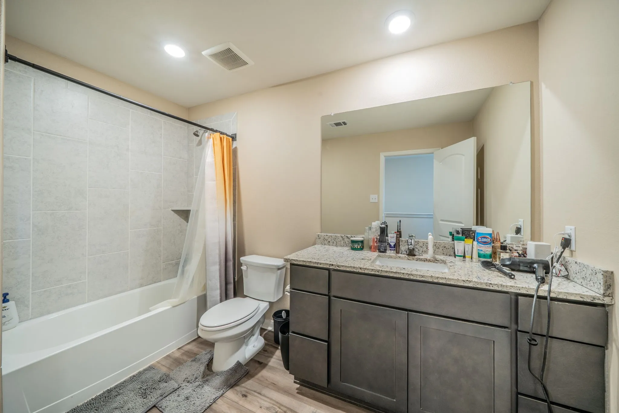 Bathroom featuring a tub and shower combination with light-toned wall tile, a built-in shower niche, and a dark-finish vanity with a speckled countertop and integrated sink