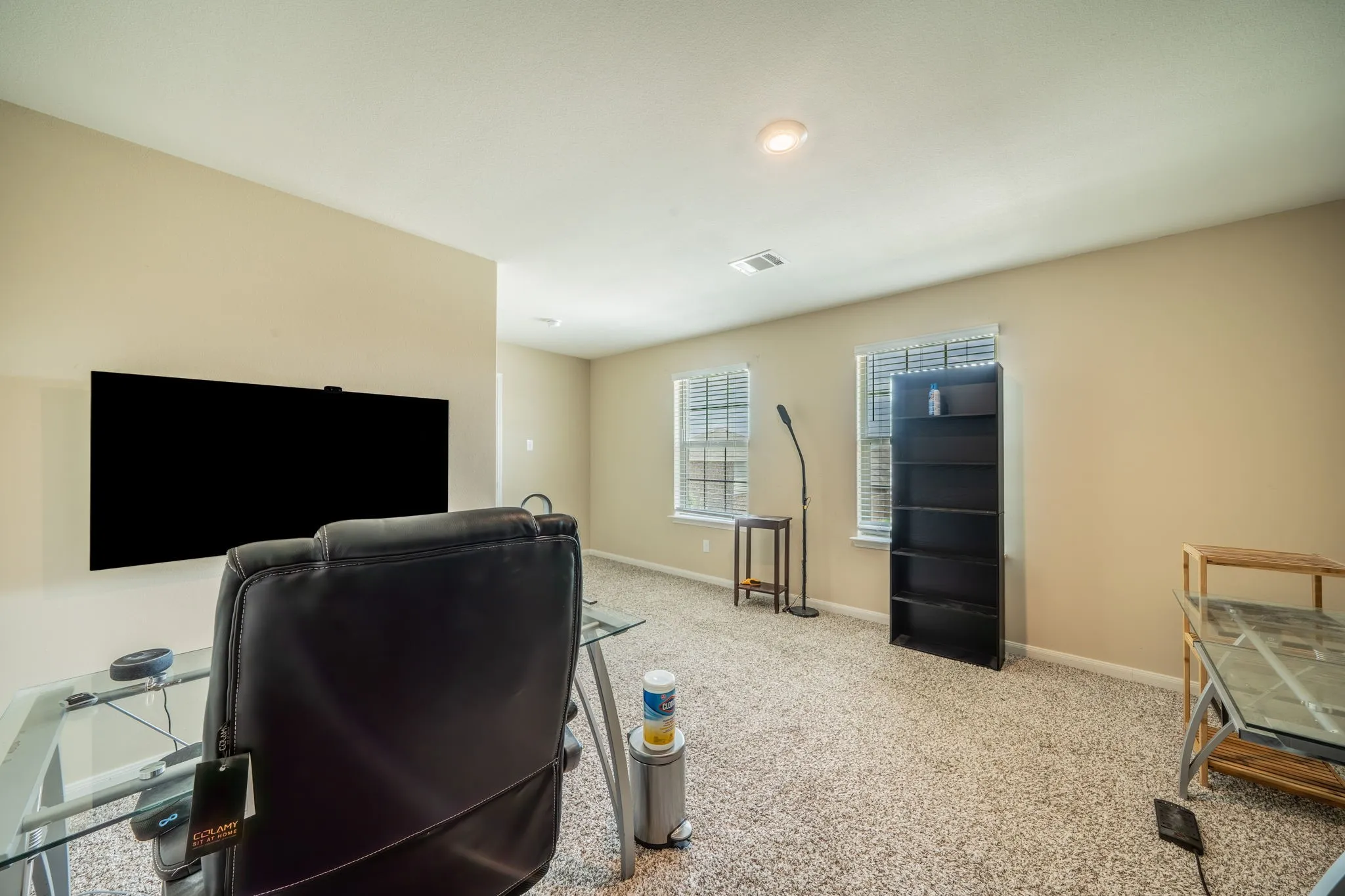 Spacious room featuring neutral wall paint, recessed lighting, two windows with blinds, and carpet flooring