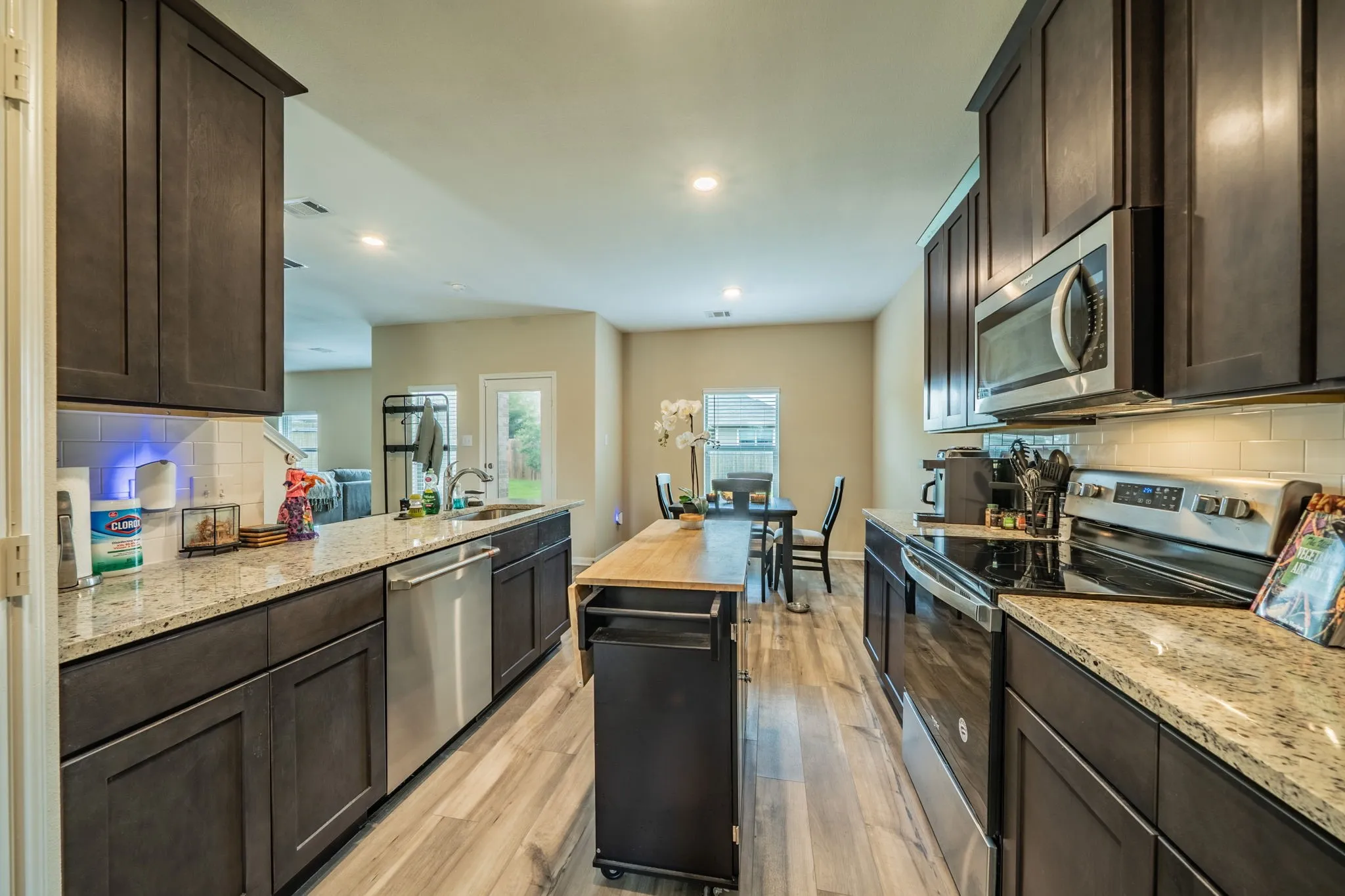 Contemporary kitchen featuring dark wood cabinetry, light-toned granite countertops, and stainless steel appliances