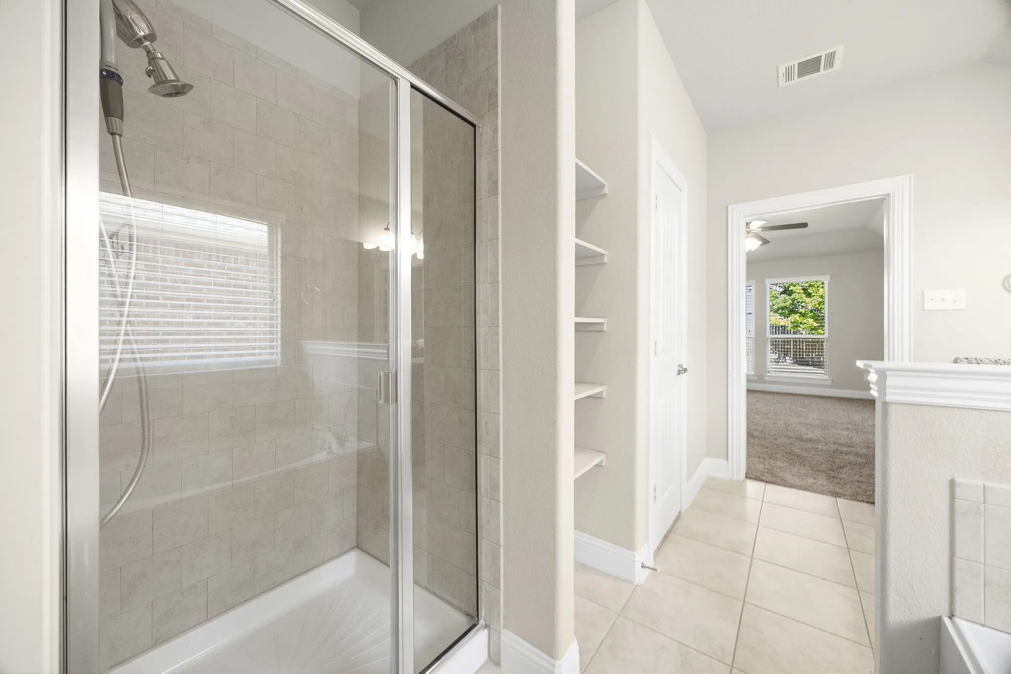 Separate shower and shelving in primary bathroom.