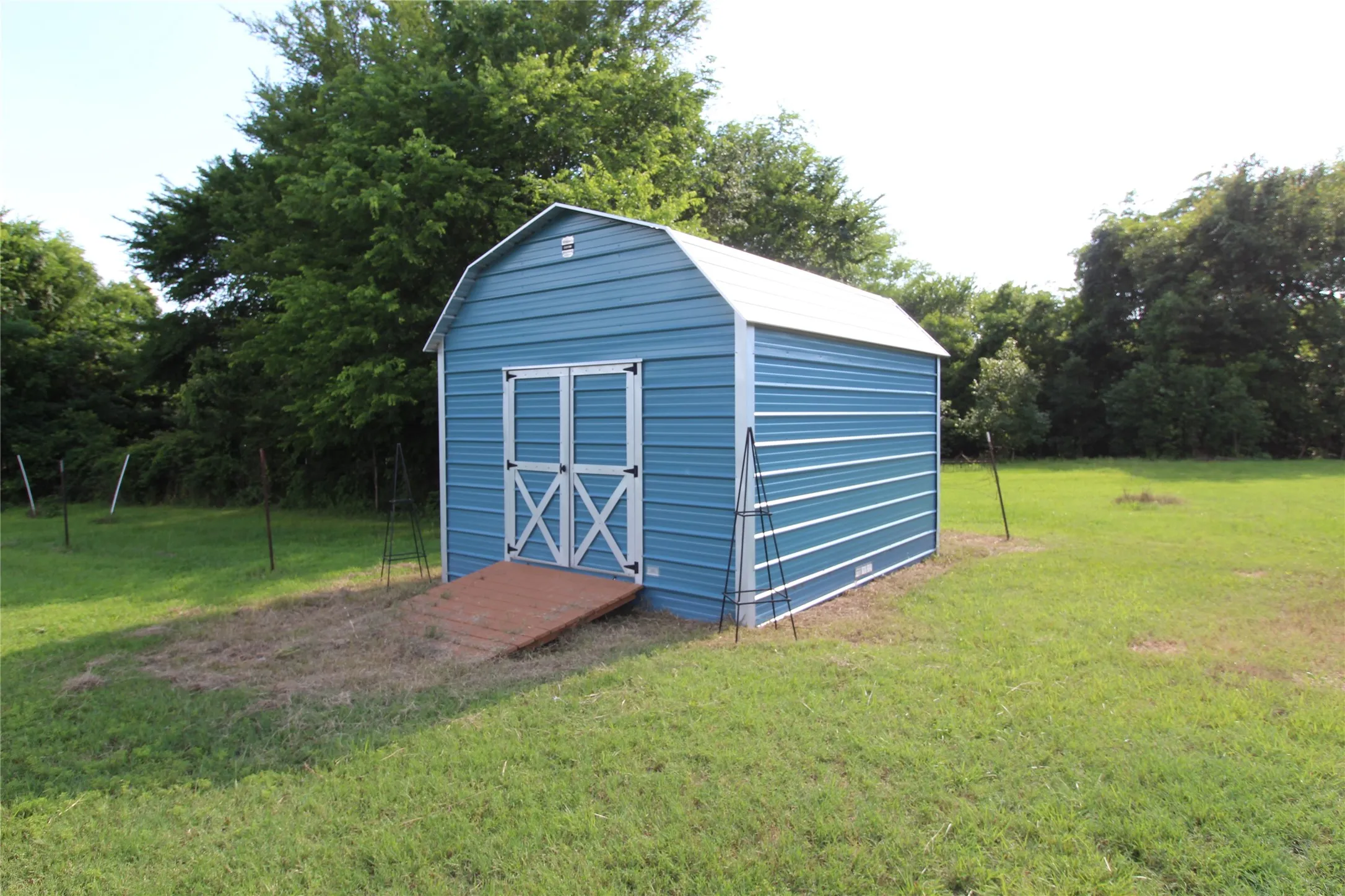 Freestanding blue metal storage shed with white trim and double doors