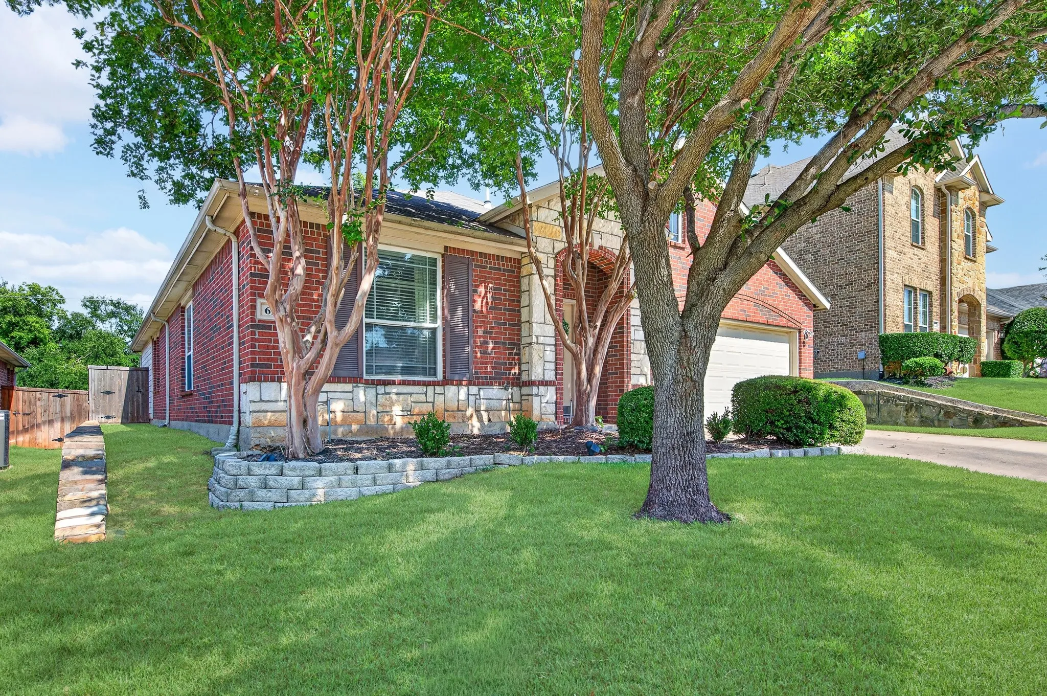 Red brick exterior with stone accent detailing and an attached garage
