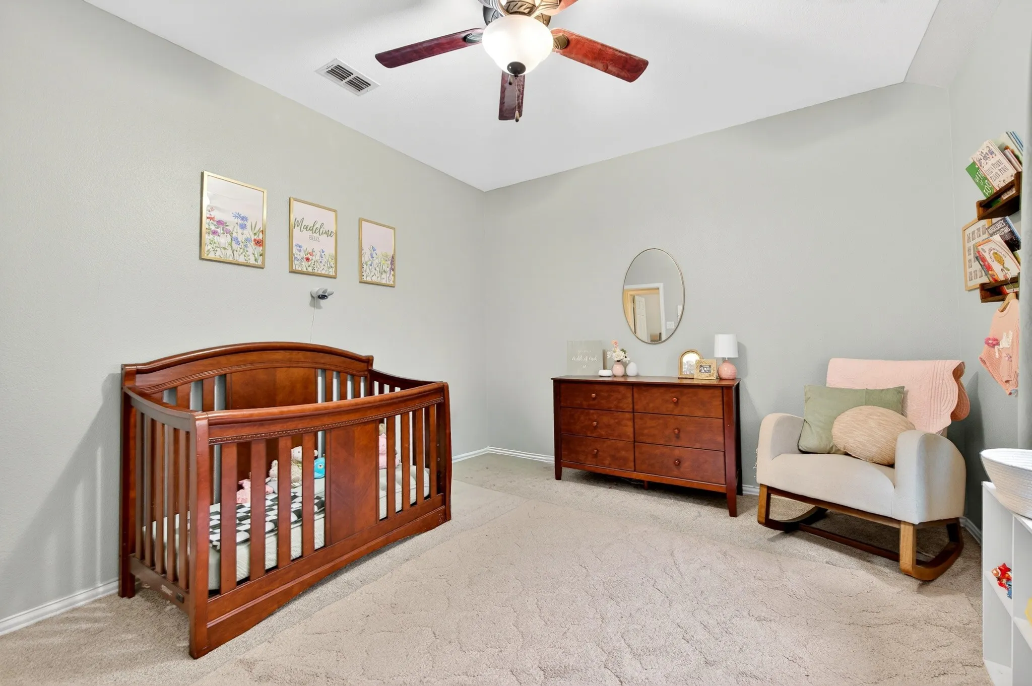 Carpeted room featuring a ceiling fan with light fixture, light gray walls, and a recessed air vent