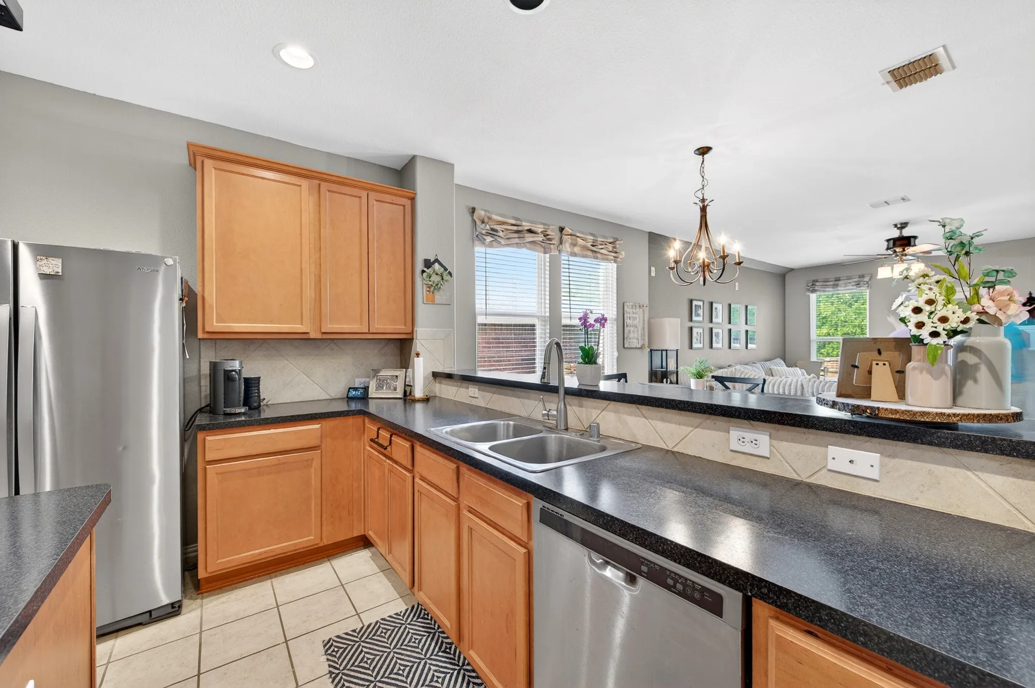 Kitchen featuring light wood cabinetry, dark countertops, and a tile backsplash