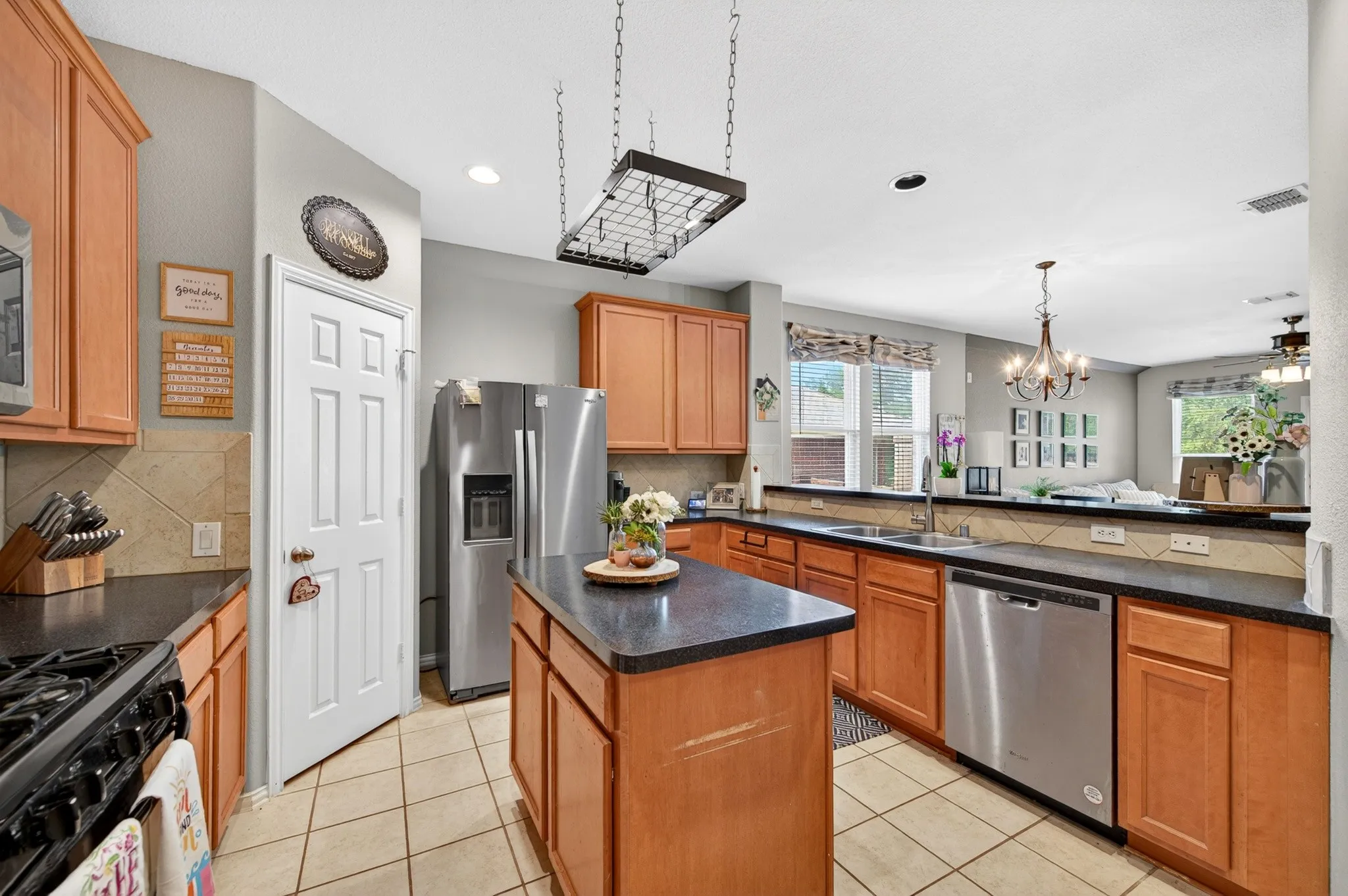 Kitchen featuring wood cabinetry, dark countertops, a central island, stainless steel appliances, and tile flooring