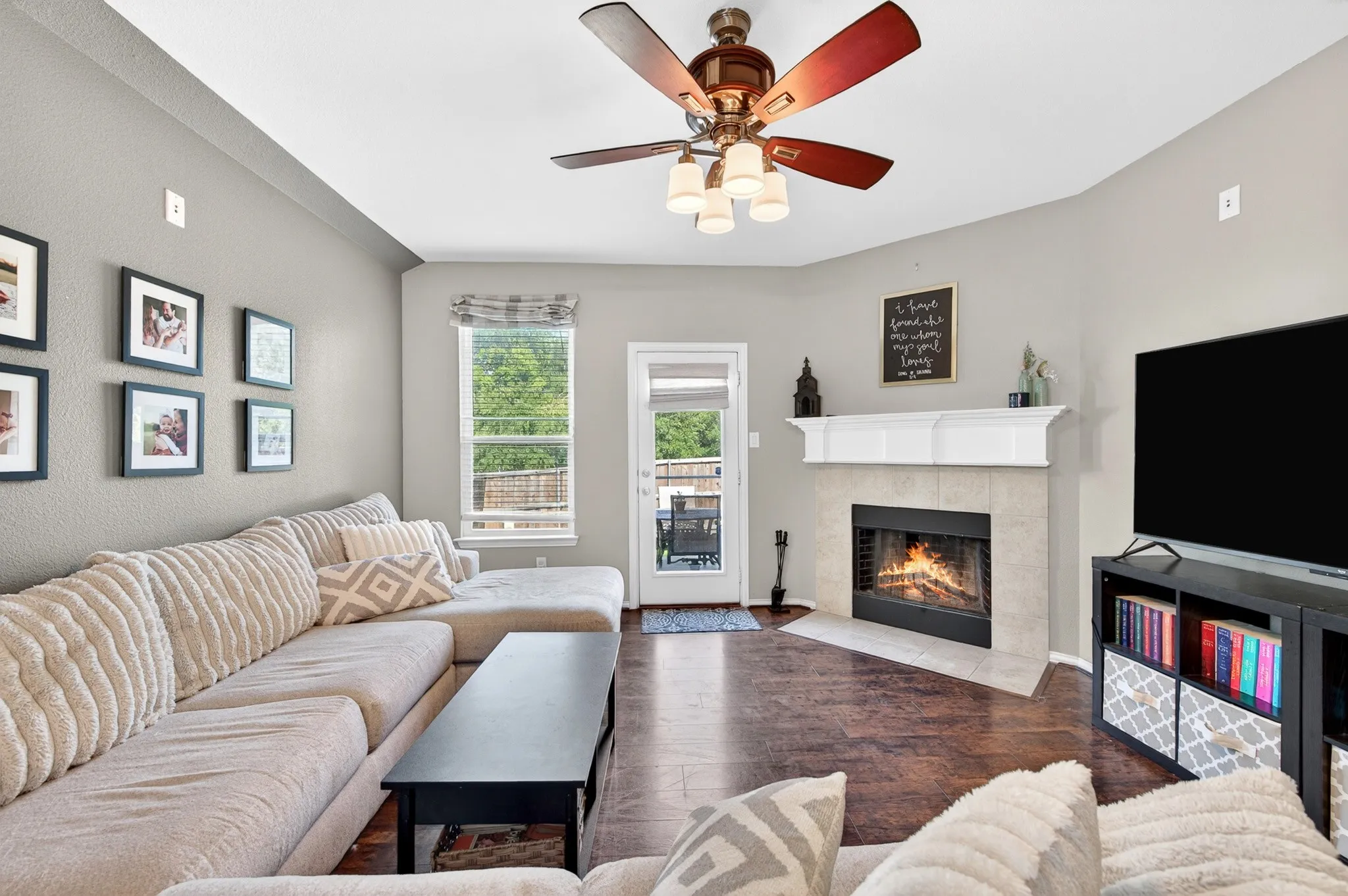 Living room featuring a fireplace with a light-toned tile surround and a classic white mantel