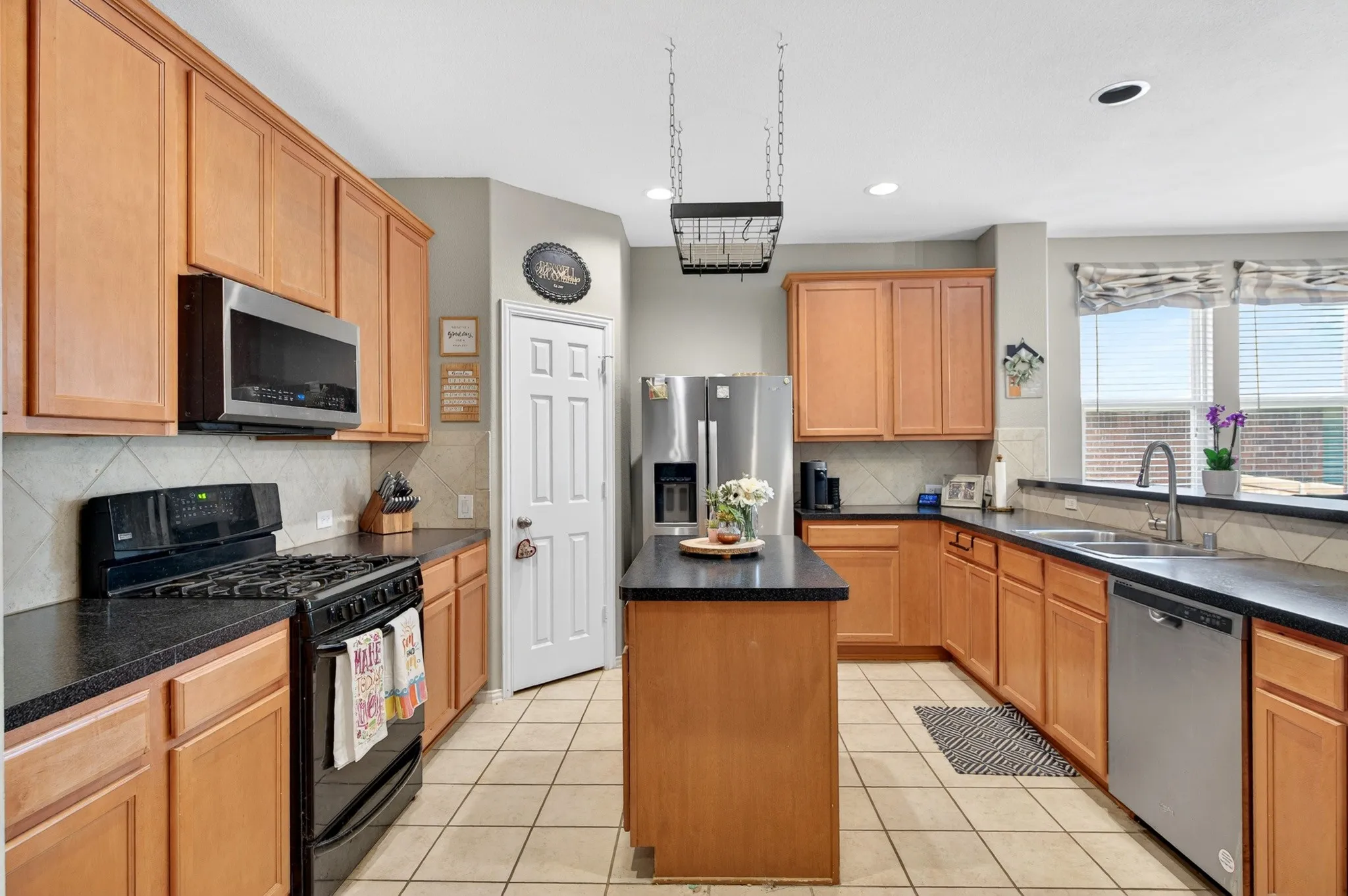 Well-appointed kitchen featuring wood-finish cabinetry, dark countertops, and tile flooring