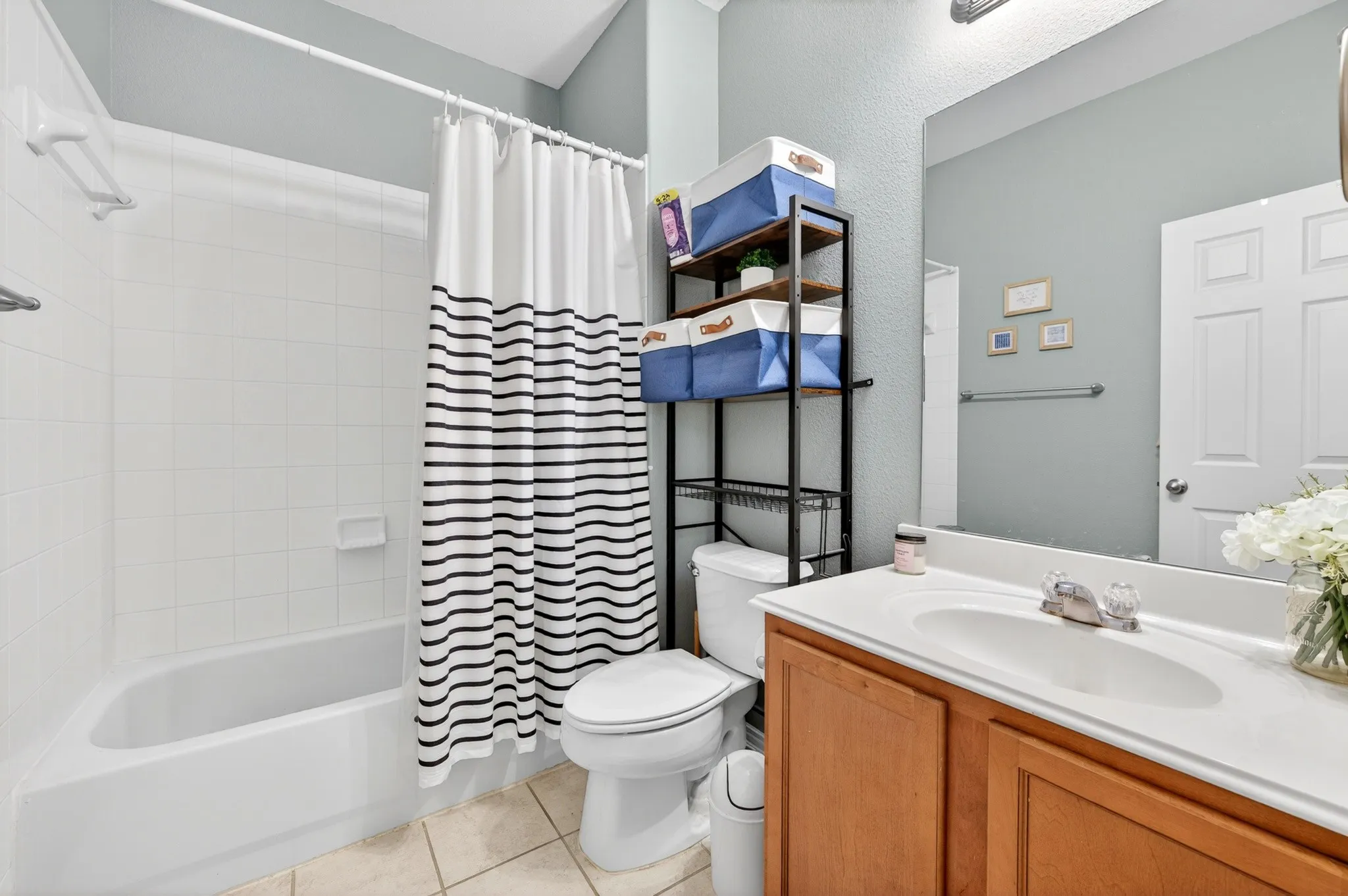Bathroom featuring a white bathtub, ceramic tile flooring, wood-finish vanity with an integrated sink, and an overhead light fixture