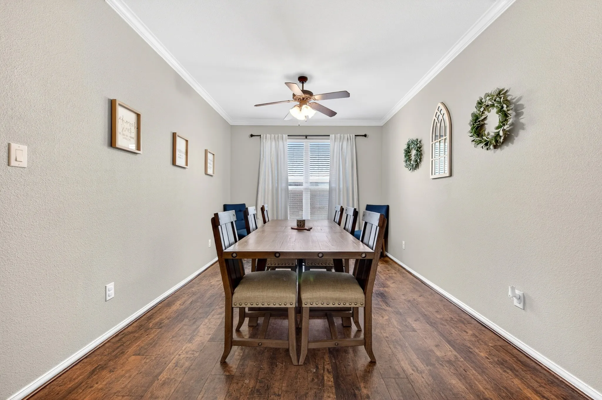 Elongated room featuring wood-finish flooring, light-toned walls, and crown molding