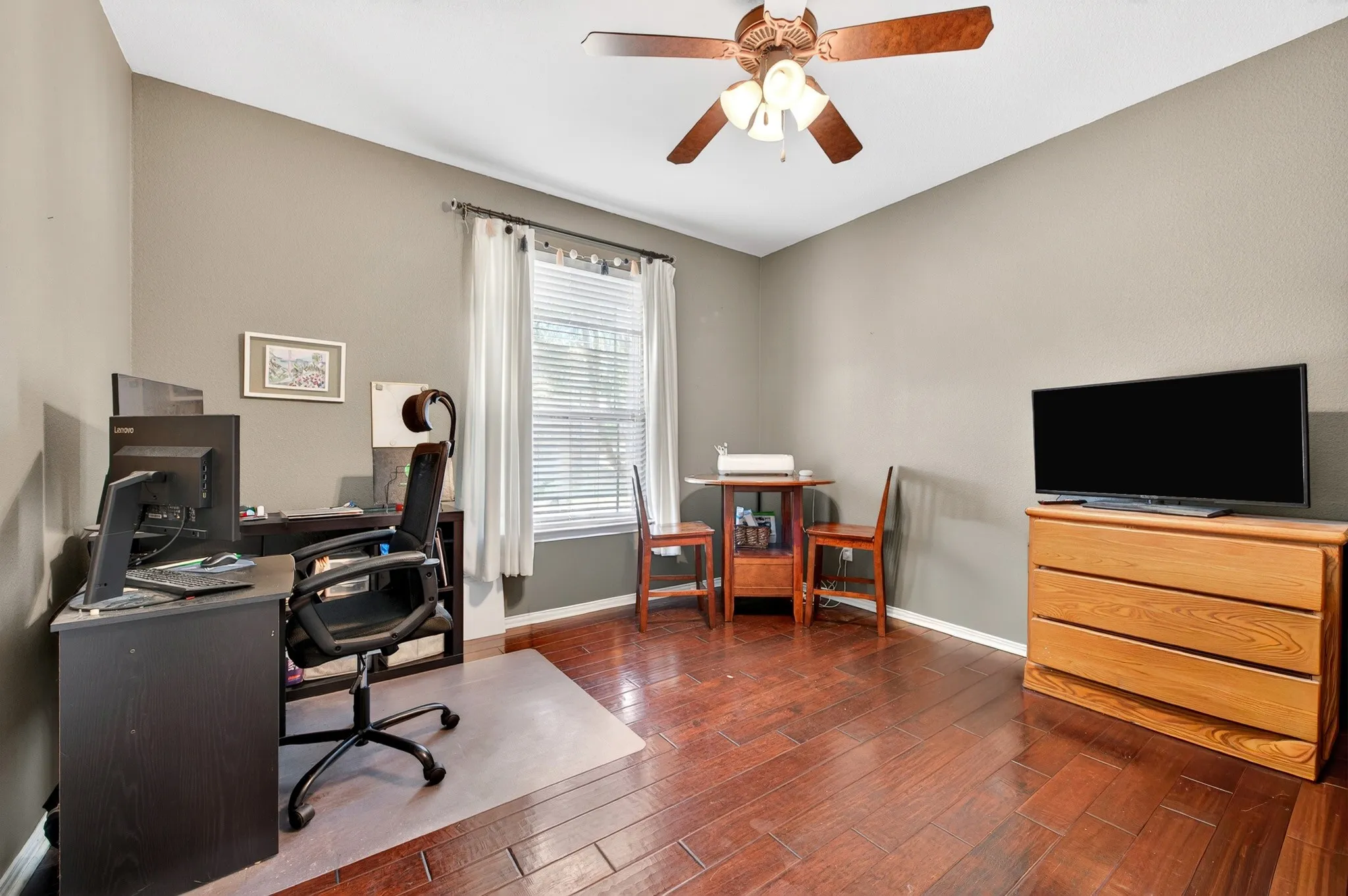 Interior room featuring wood-finish flooring, a ceiling fan with integrated lighting, and neutral wall tones