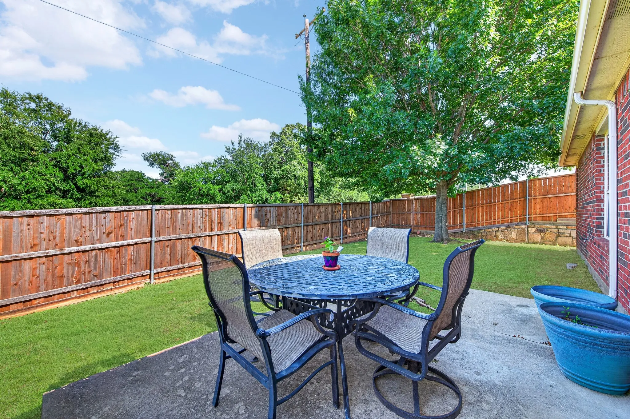 Private backyard featuring a concrete patio, wood privacy fencing, and a mature shade tree
