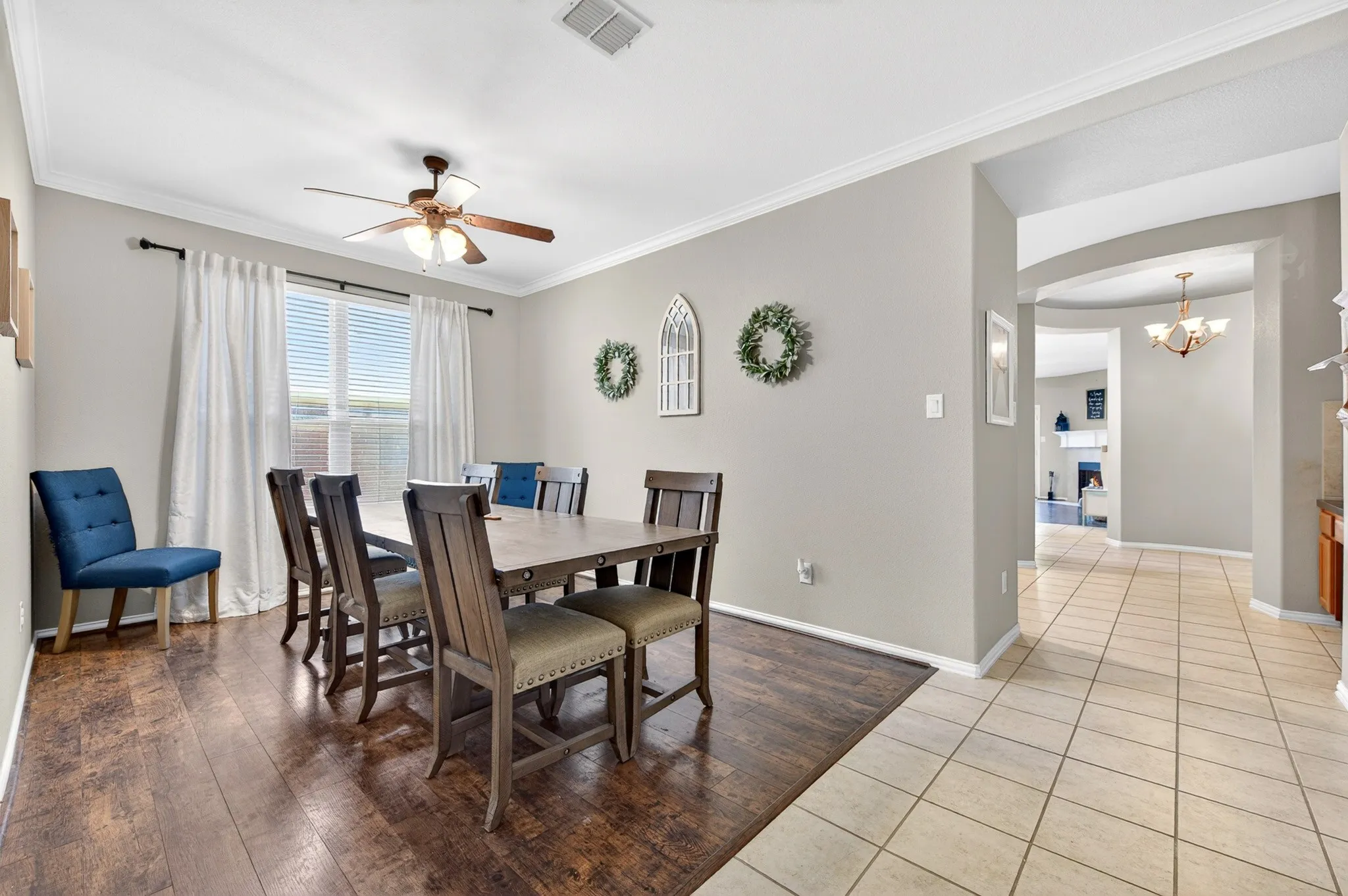 Dining area featuring wood-finish flooring, a ceiling fan with integrated lighting, and crown molding
