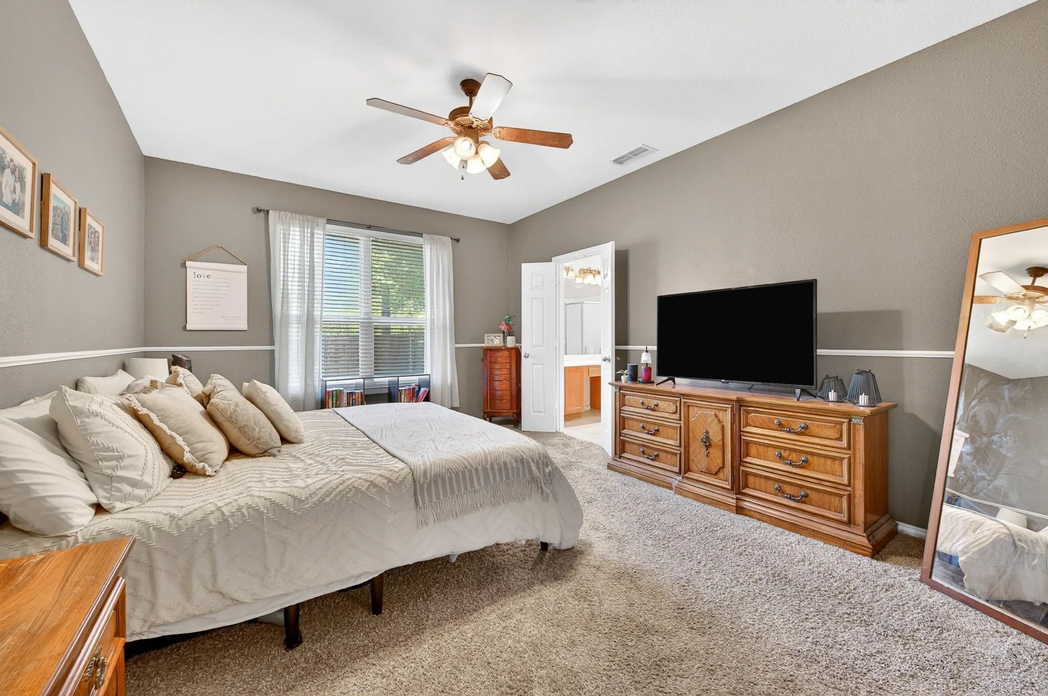 Carpeted room with a vaulted ceiling, ceiling fan, and chair rail molding