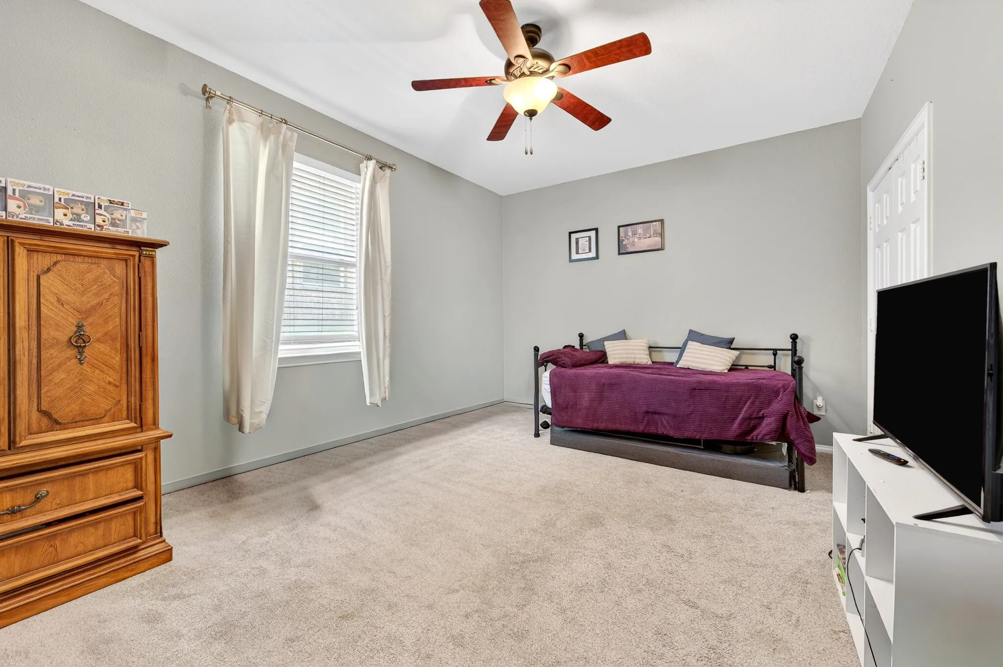 Carpeted room featuring a ceiling fan with integrated lighting, a window with blinds and drapes, and neutral wall paint