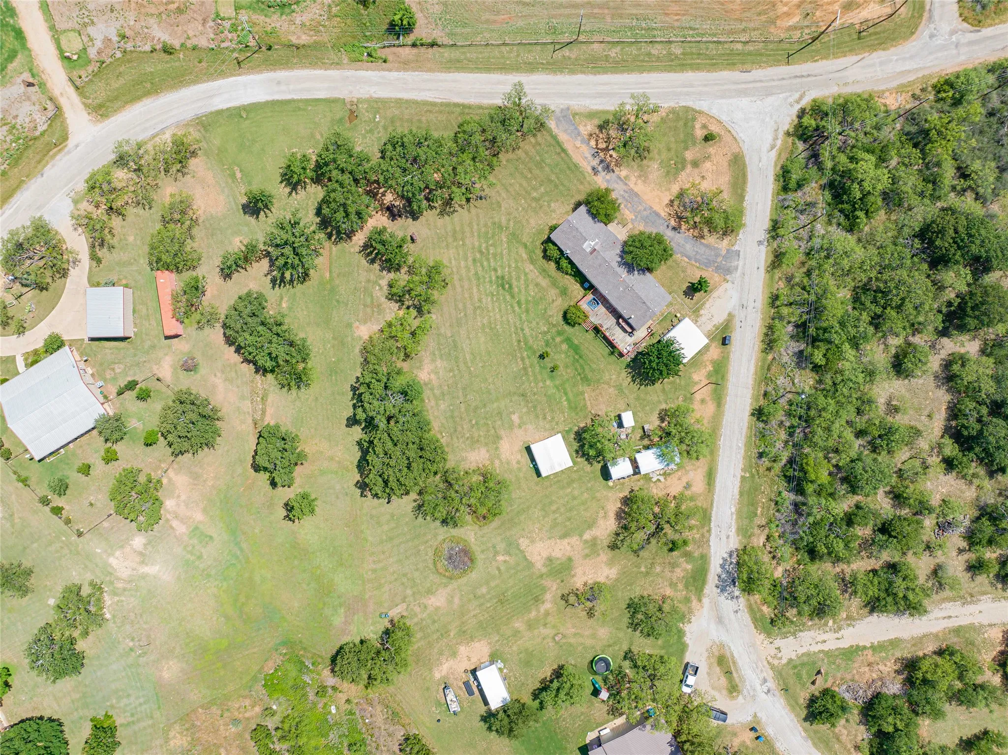 Expansive property featuring a central residence with a surrounding cleared lawn and mature trees