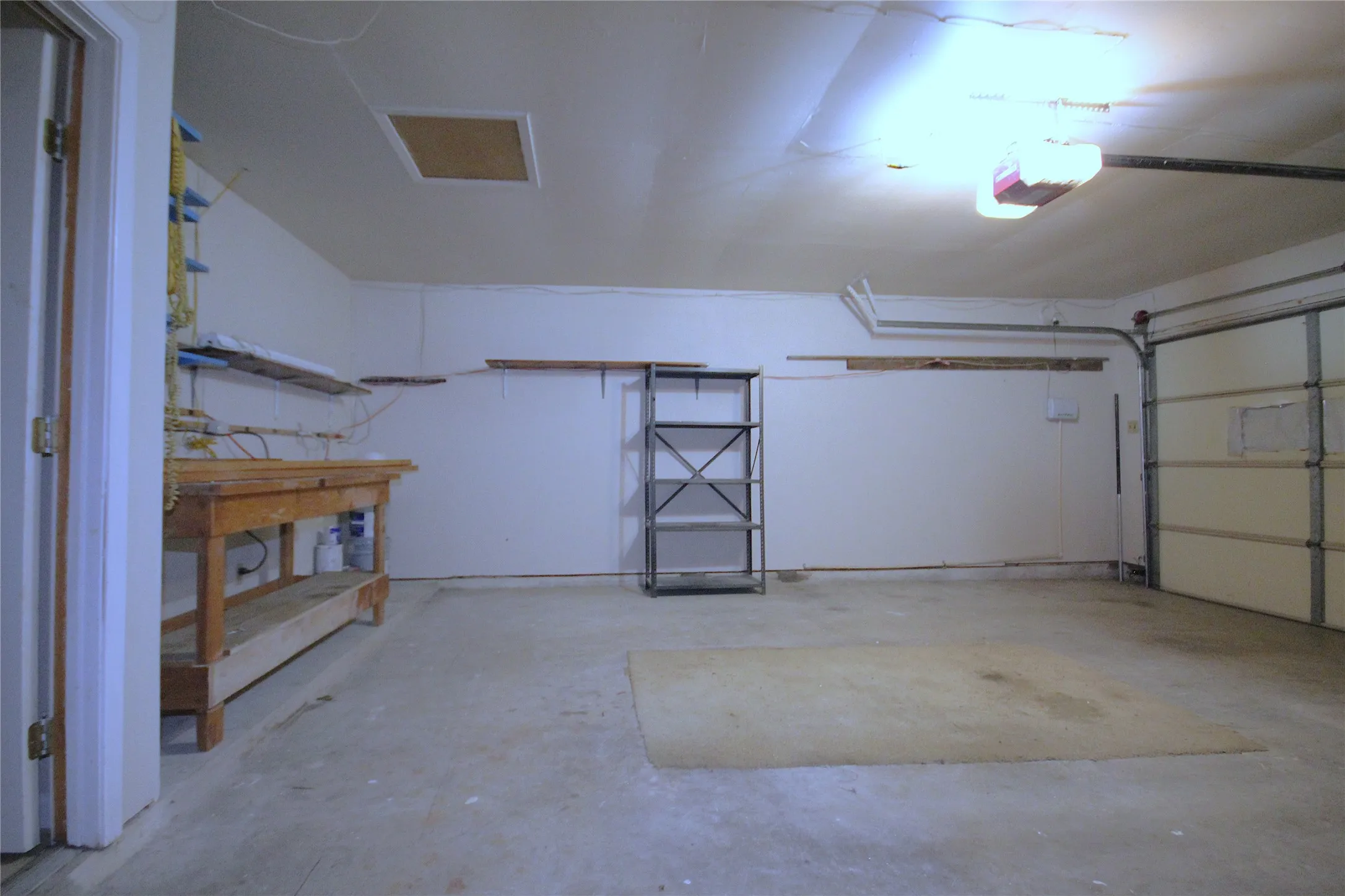 2 car attached garage with workbench area, a side door to the backyard and door leading into the utility room.