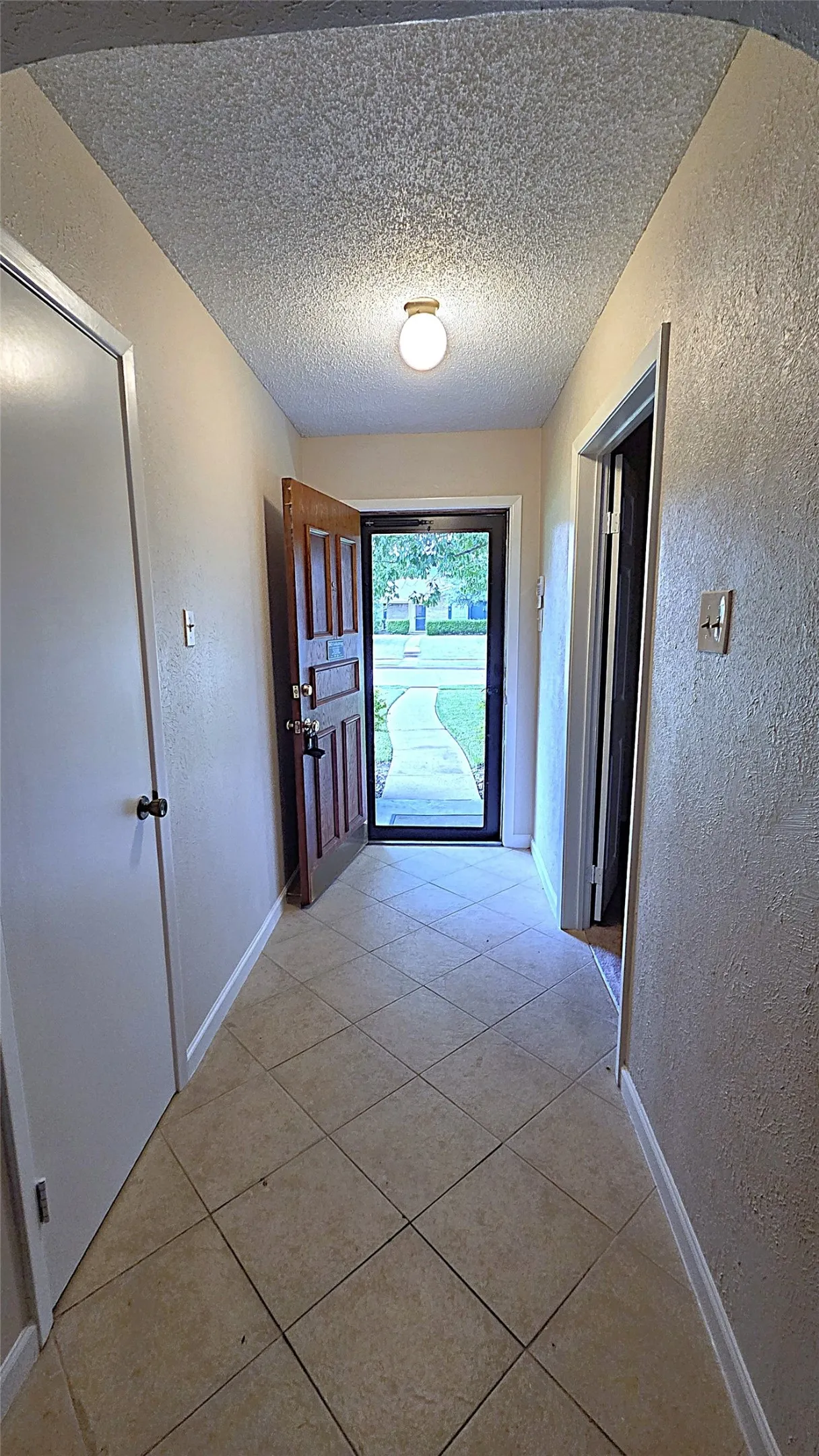 Tiled foyer, coat closet and thresholds into the formal dining room and living space.