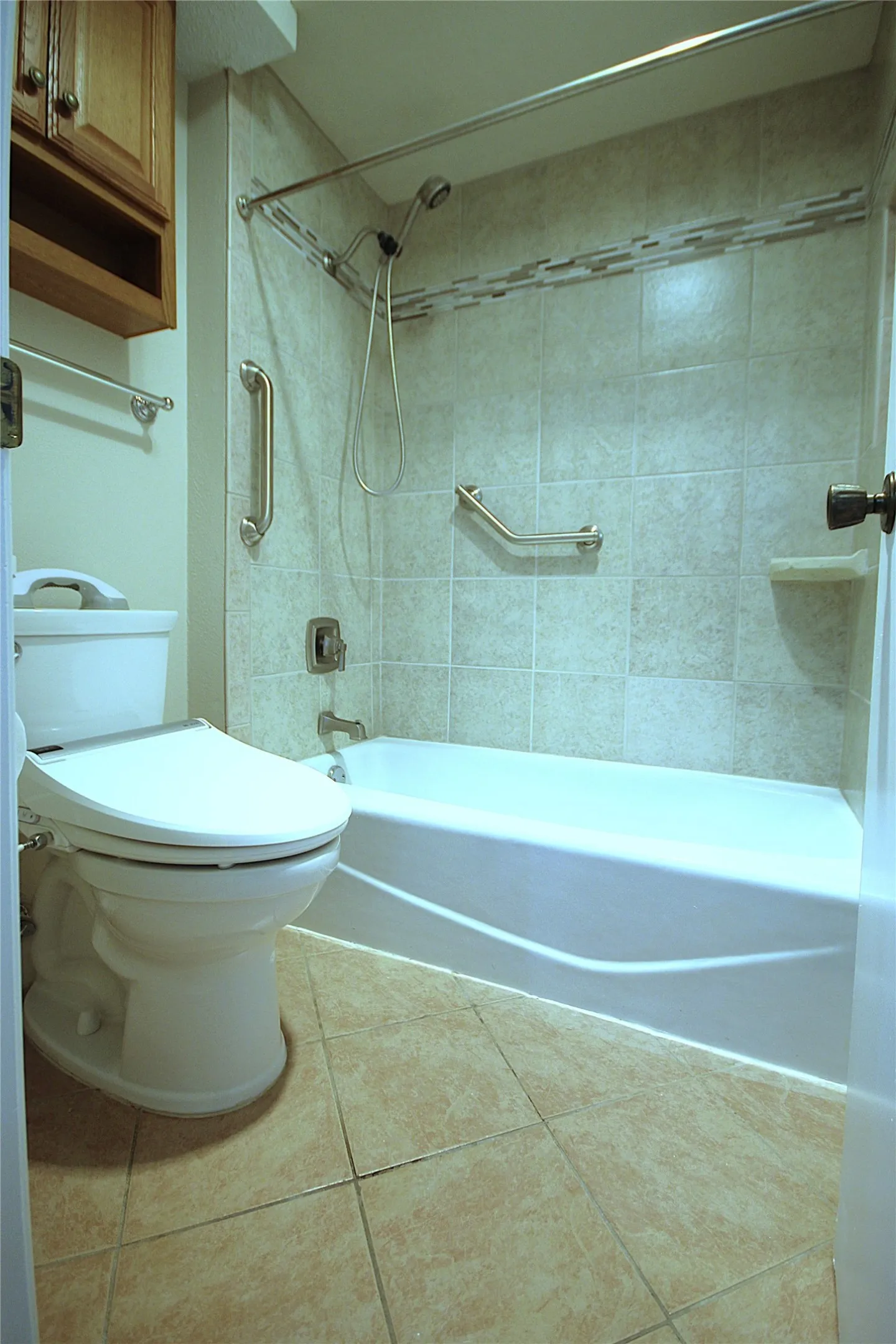 Updated primary bath with storage cabinet, tiled surround and floor, tub and fixtures.