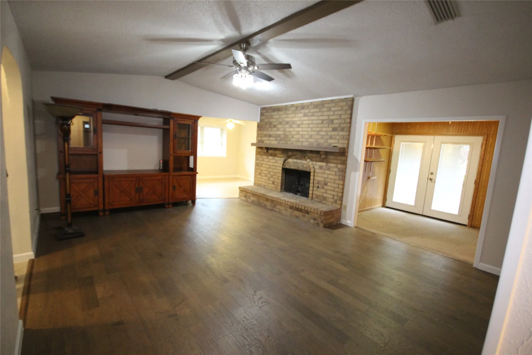 Living area offers a beamed ceilling, brick floor to ceiling fireplace with hearth and mantle, flex space with French doors previously used as an office yet could be used many ways